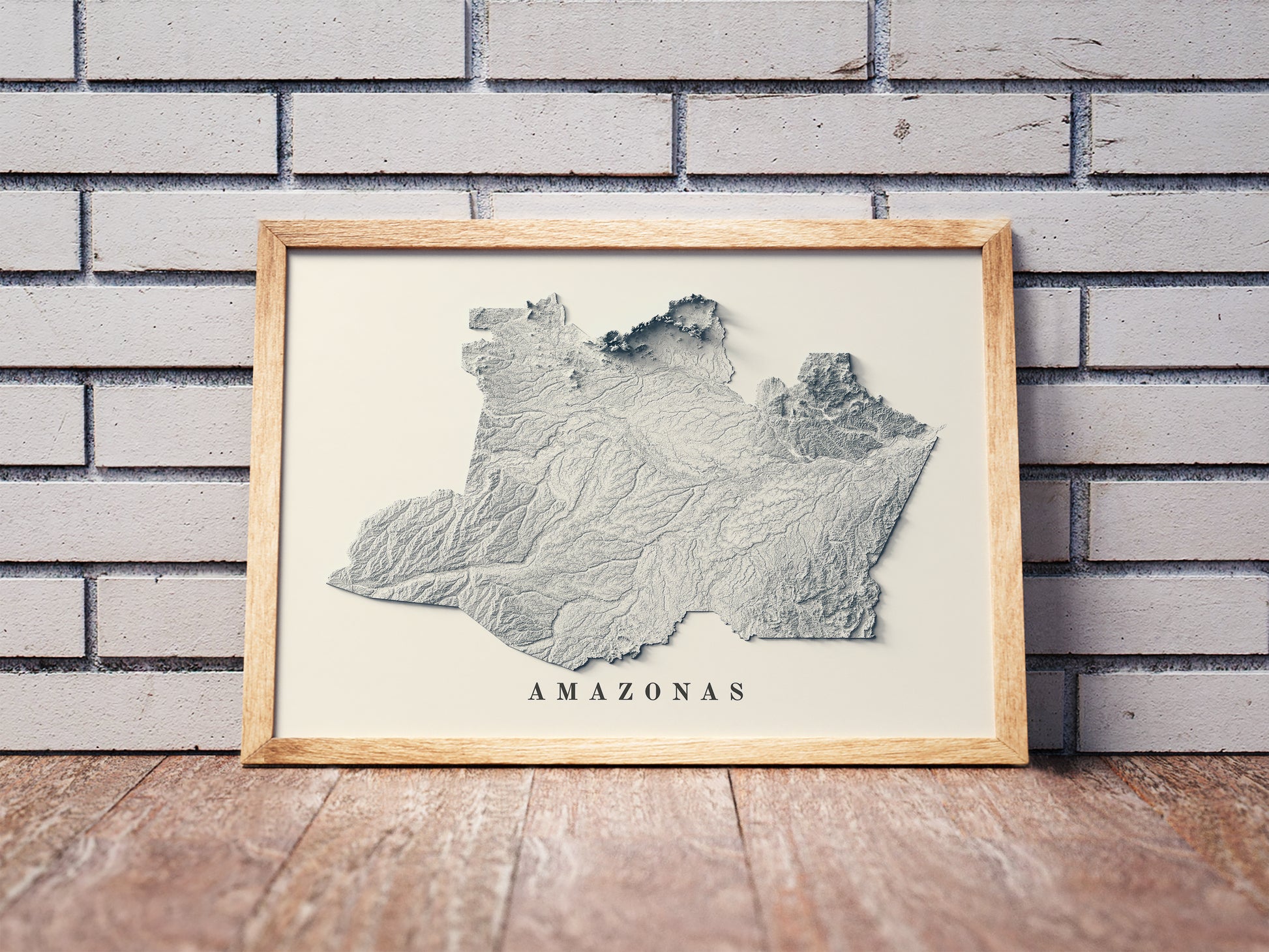 Amazonas State (Brazil) shaded relief map in a wooden frame. Realistic terrain art print for home decor, displayed against a brick wall