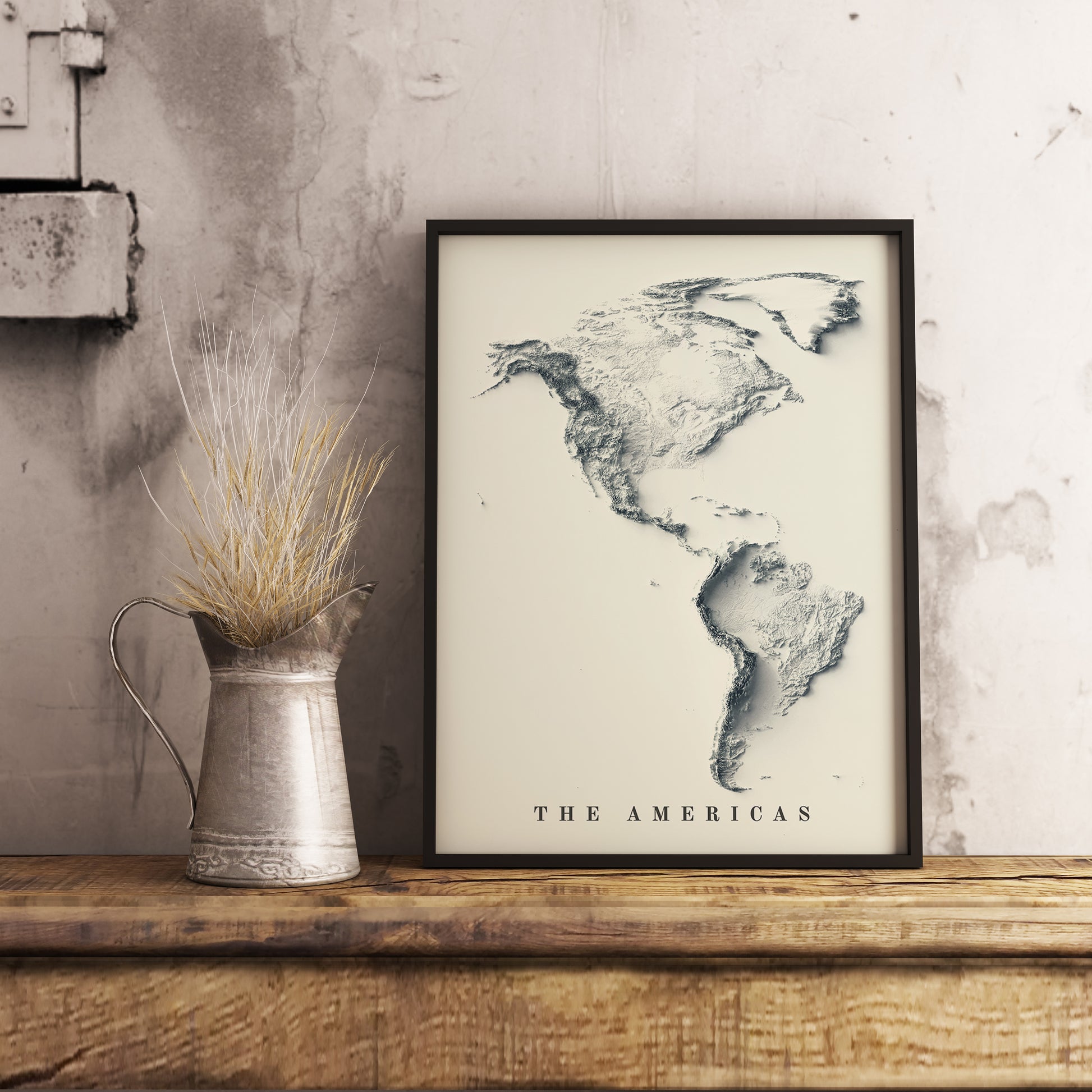 Americas shaded relief map in black frame. Realistic terrain art print for home decor, displayed on rustic wooden table