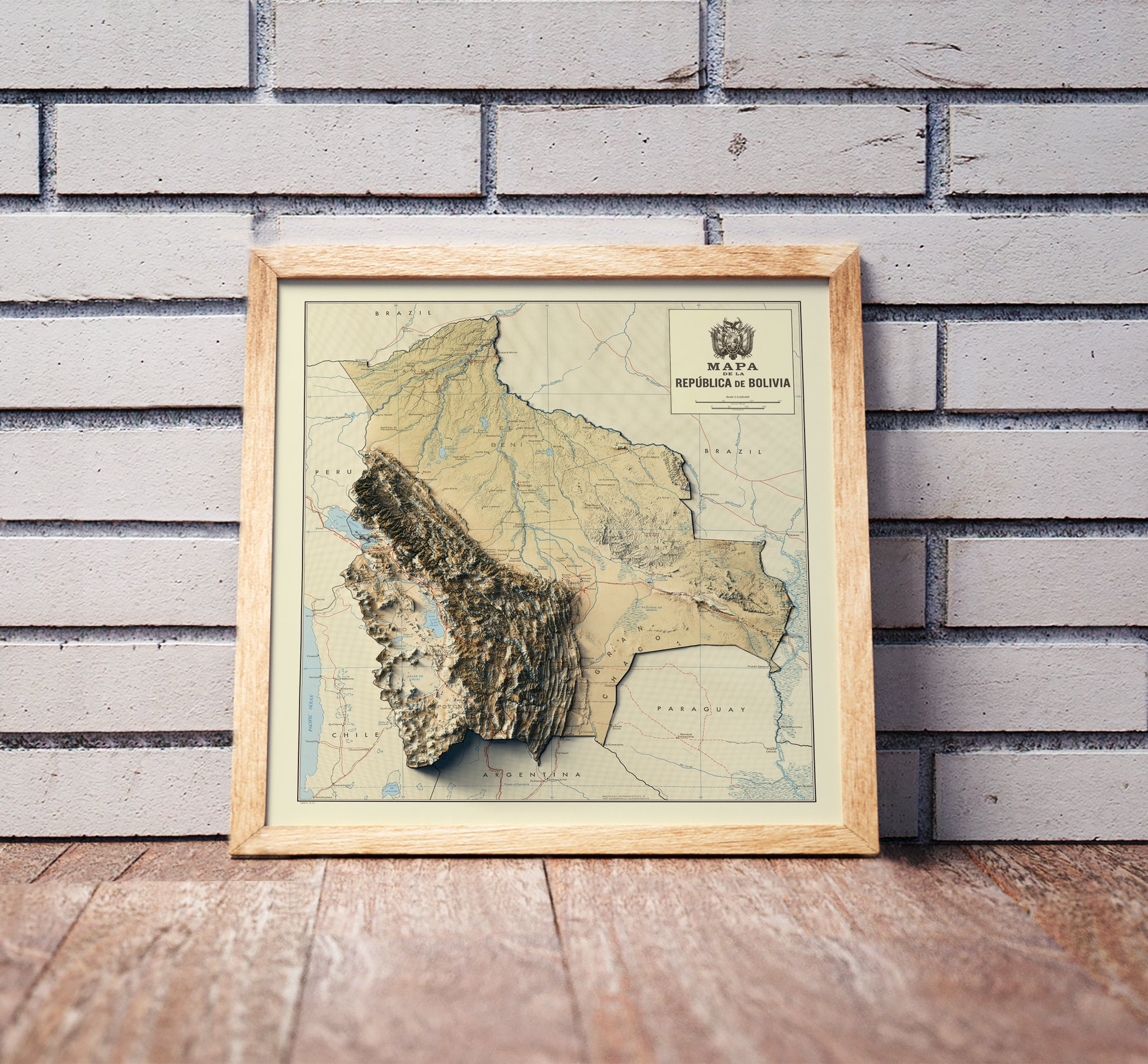 Vintage Bolivia shaded relief map in a wooden frame. Realistic terrain art print for home decor, displayed against a brick wall