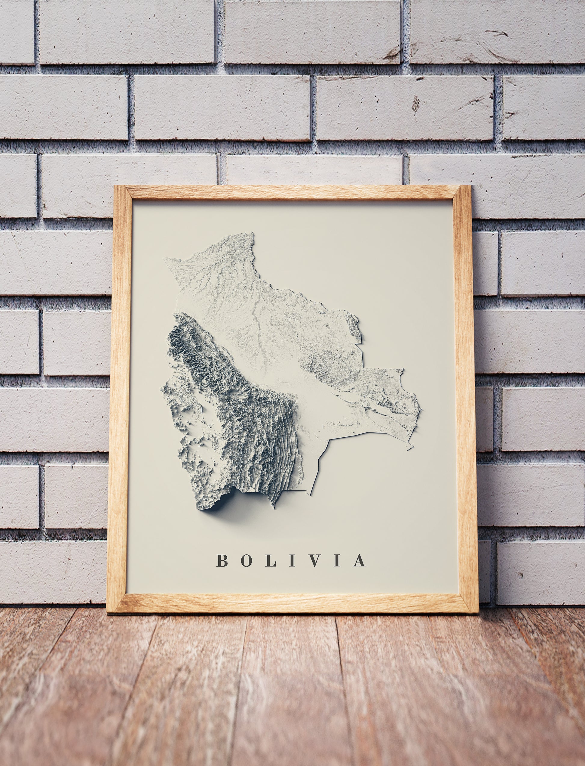 Vintage Bolivia shaded relief map in a wooden frame. Realistic terrain art print for home decor, displayed against a brick wall