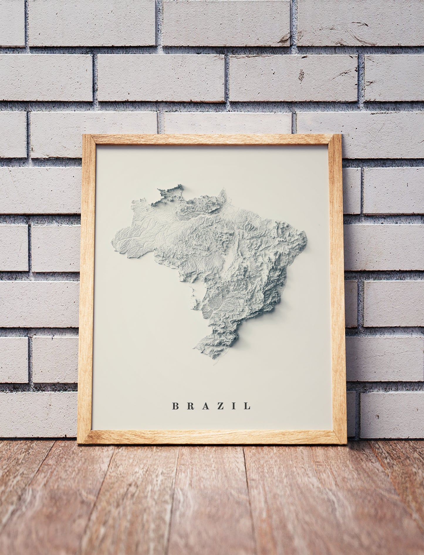 Vintage Brazil shaded relief map in a wooden frame. Realistic terrain art print for home decor, displayed against a brick wall