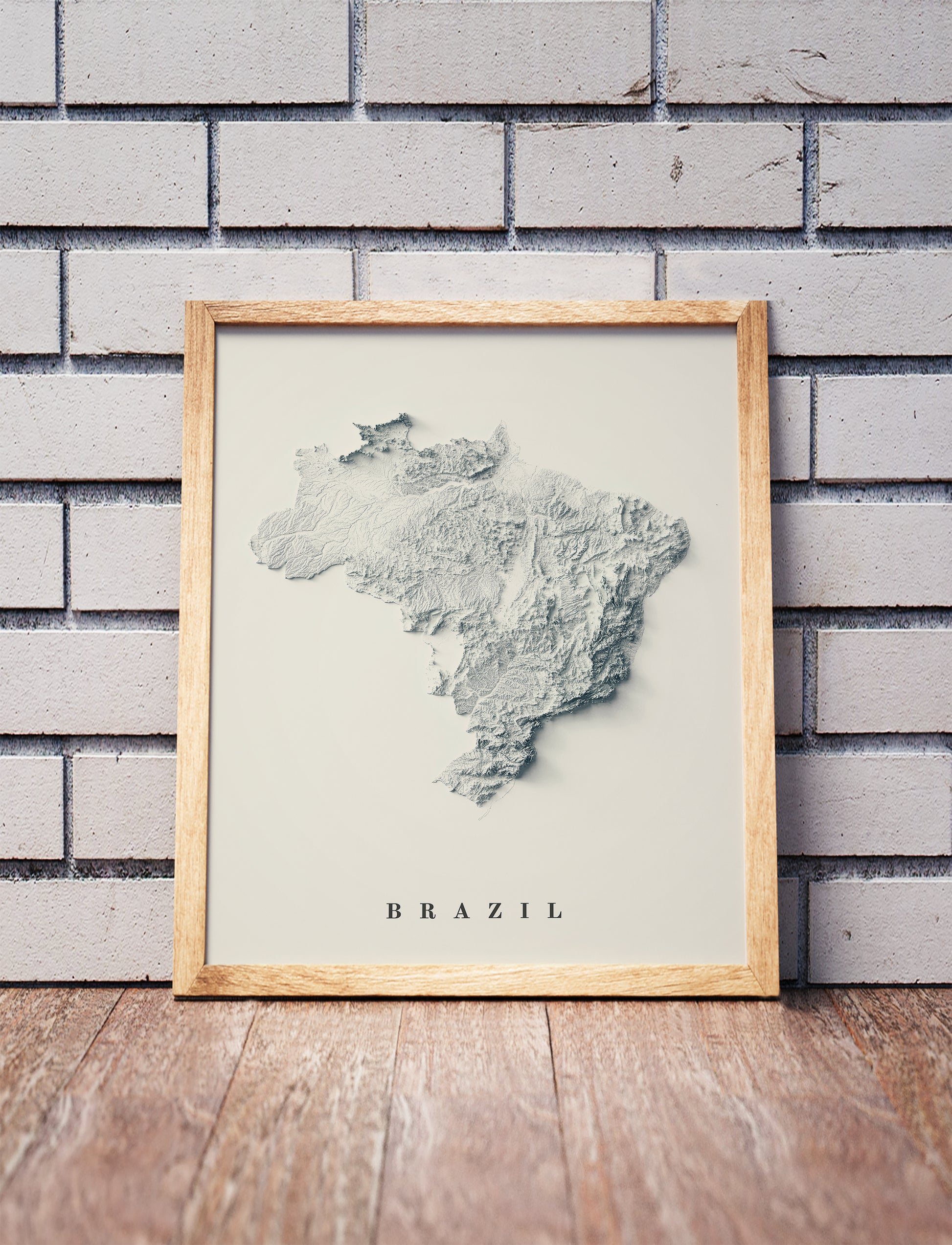 Vintage Brazil shaded relief map in a wooden frame. Realistic terrain art print for home decor, displayed against a brick wall