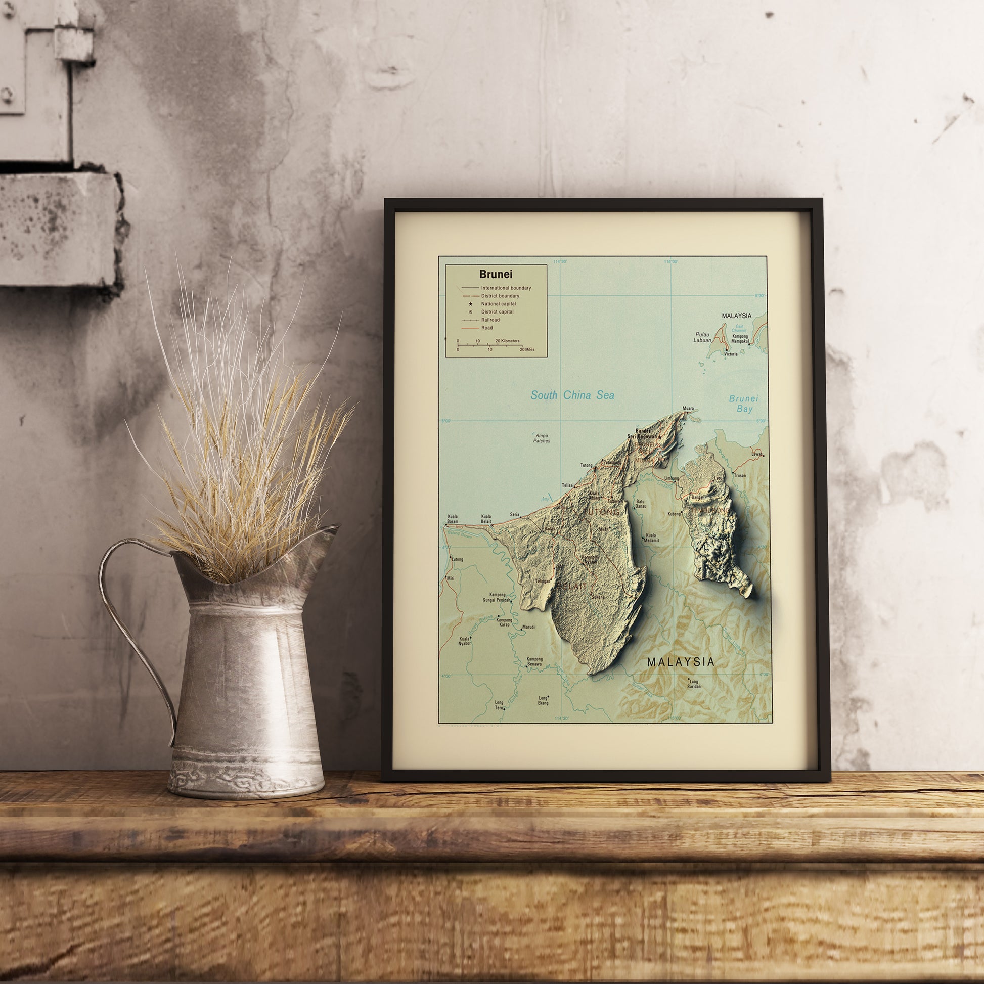 Vintage Brunei shaded relief map in black frame. Realistic terrain art print for home decor, displayed on rustic wooden table