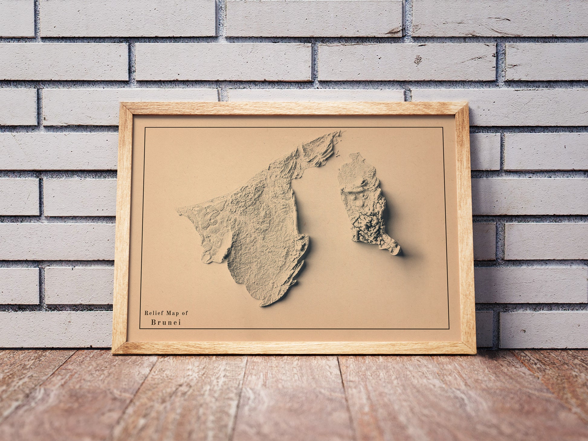 Vintage Brunei shaded relief map in a wooden frame. Realistic terrain art print for home decor, displayed against a brick wall