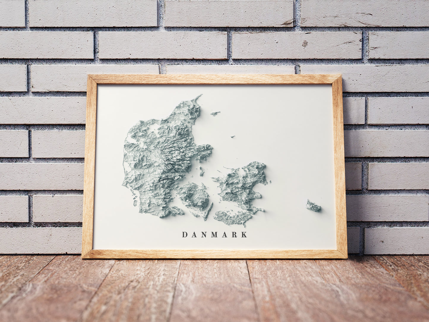 Vintage Denmark shaded relief map in a wooden frame. Realistic terrain art print for home decor, displayed against a brick wall