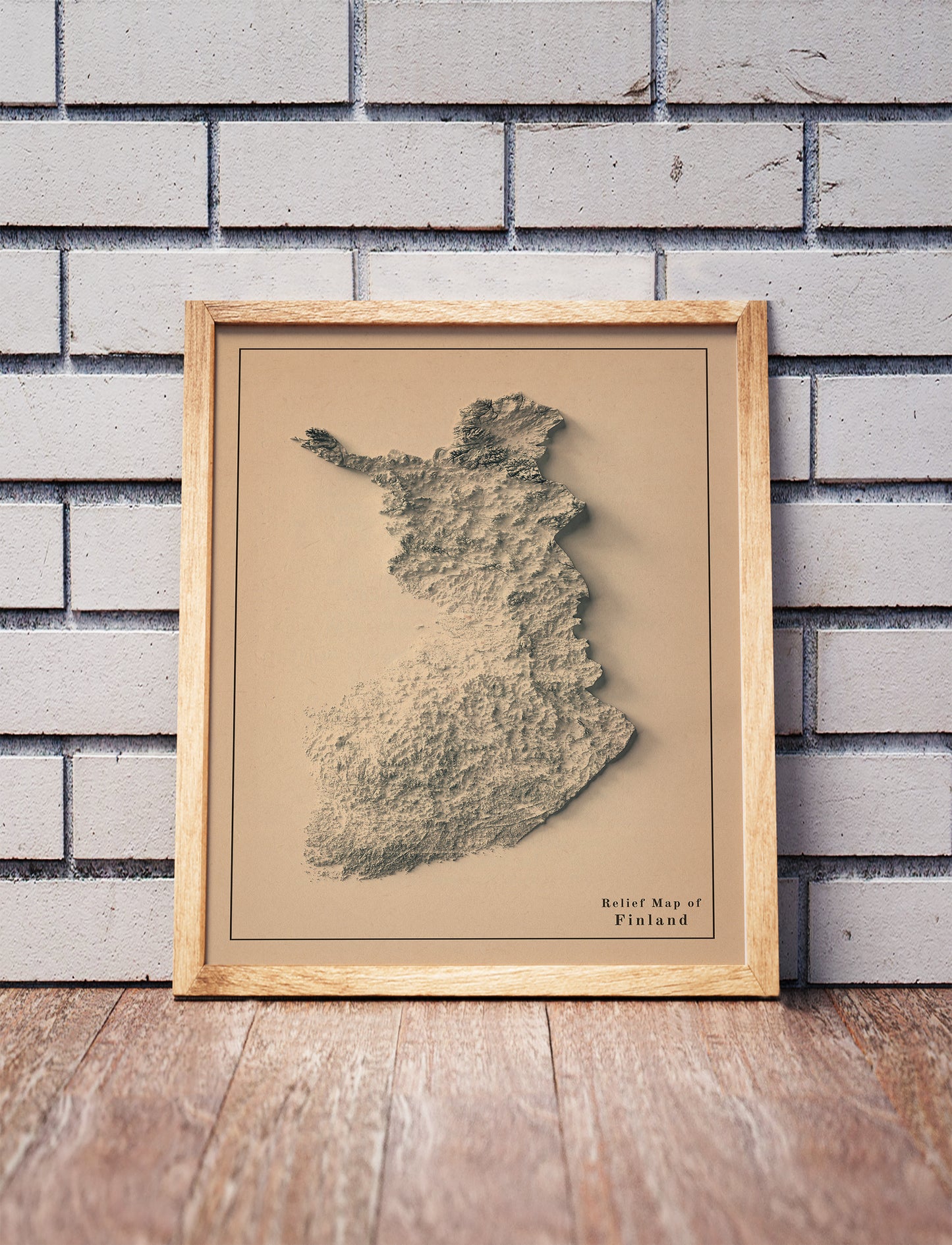 Vintage Finland shaded relief map in a wooden frame. Realistic terrain art print for home decor, displayed against a brick wall