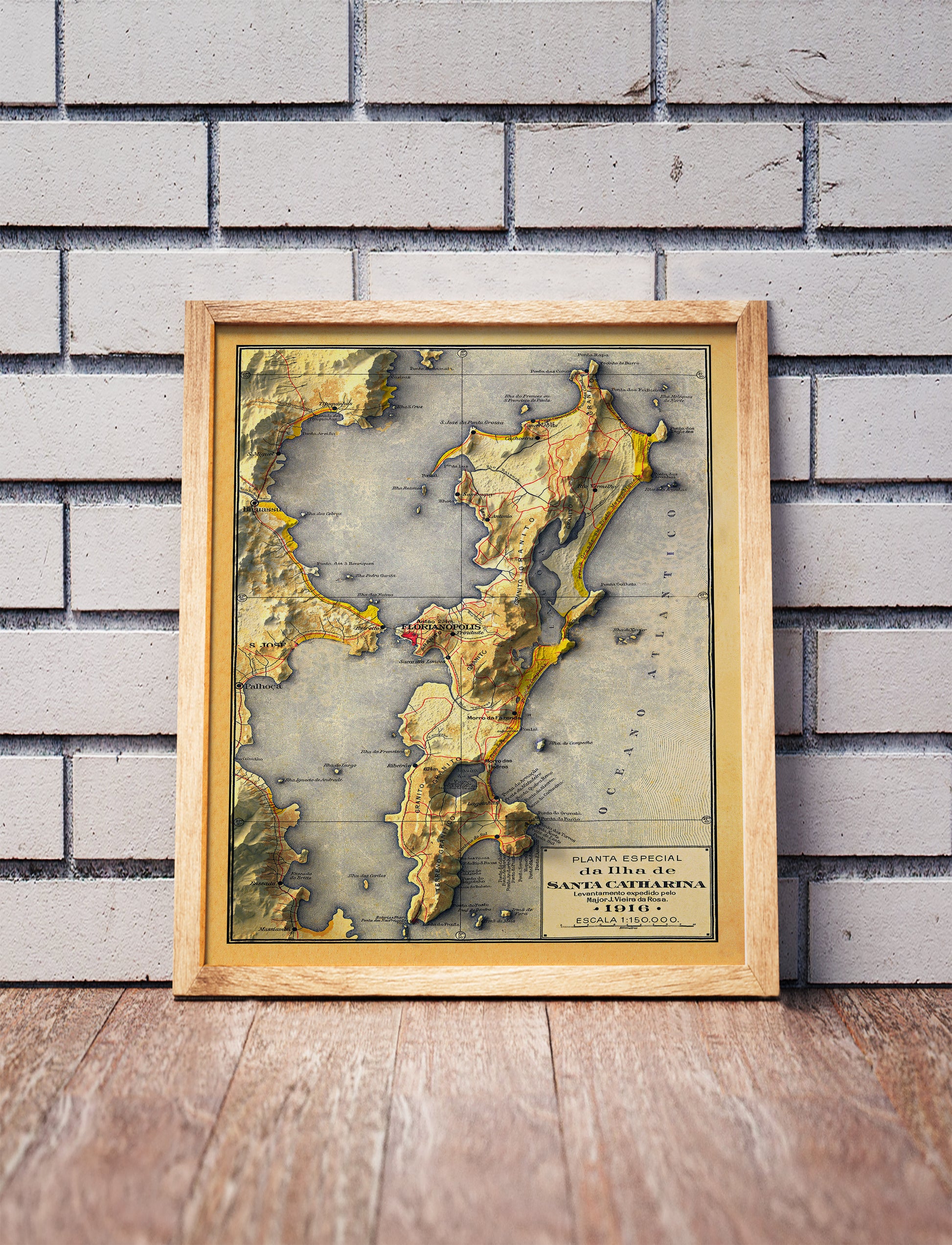 Vintage Florianopolis (Brazil) shaded relief map in a wooden frame. Realistic terrain art print for home decor, displayed against a brick wall