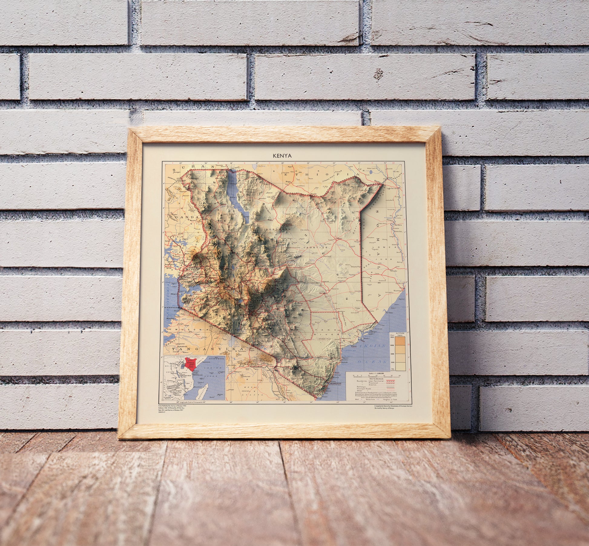 Vintage Kenya shaded relief map in a wooden frame. Realistic terrain art print for home decor, displayed against a brick wall
