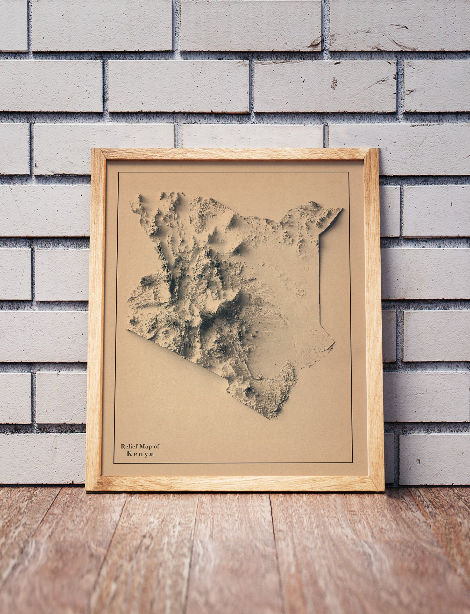 Vintage Kenya shaded relief map in a wooden frame. Realistic terrain art print for home decor, displayed against a brick wall