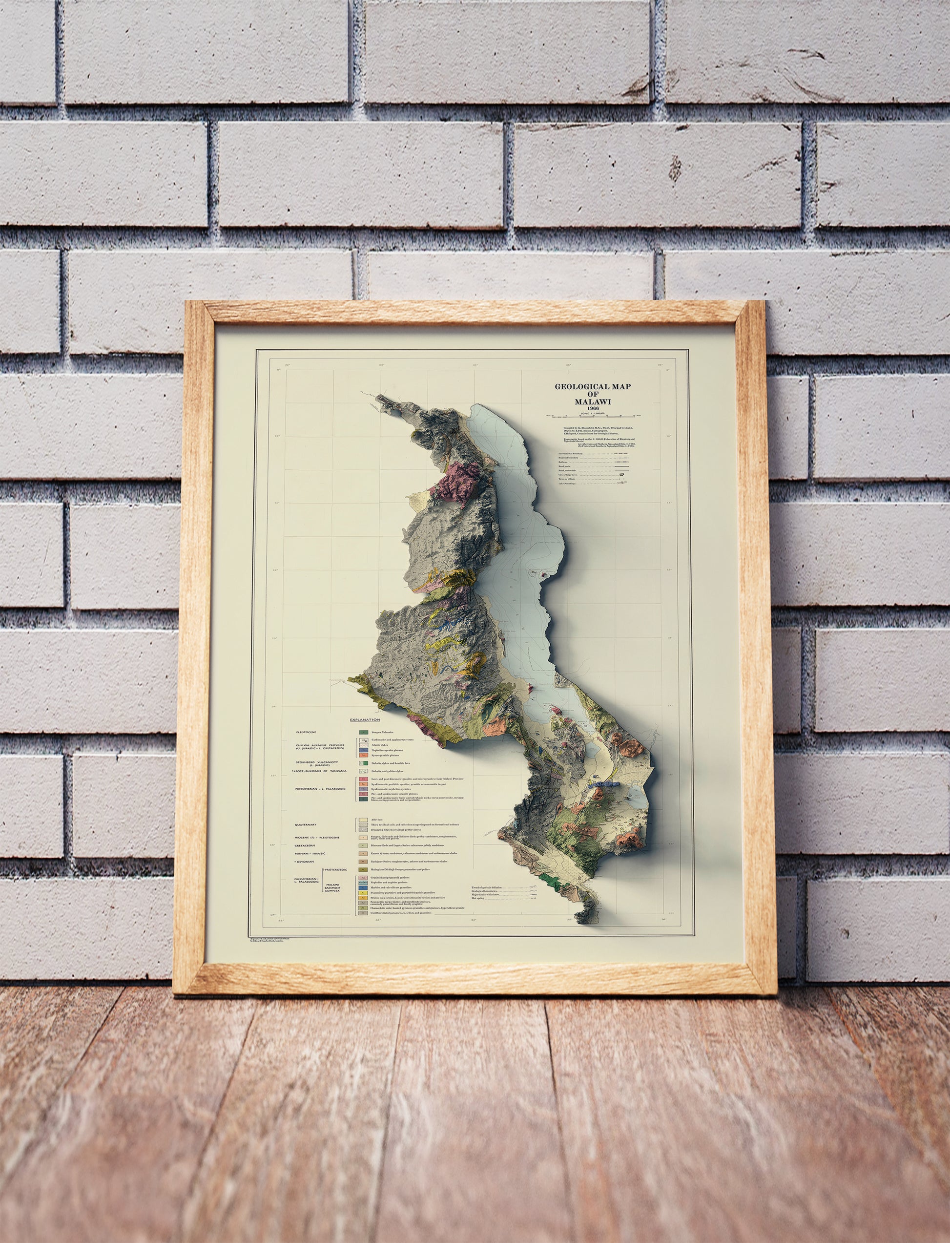 Vintage Malawi shaded relief map in a wooden frame. Realistic terrain art print for home decor, displayed against a brick wall