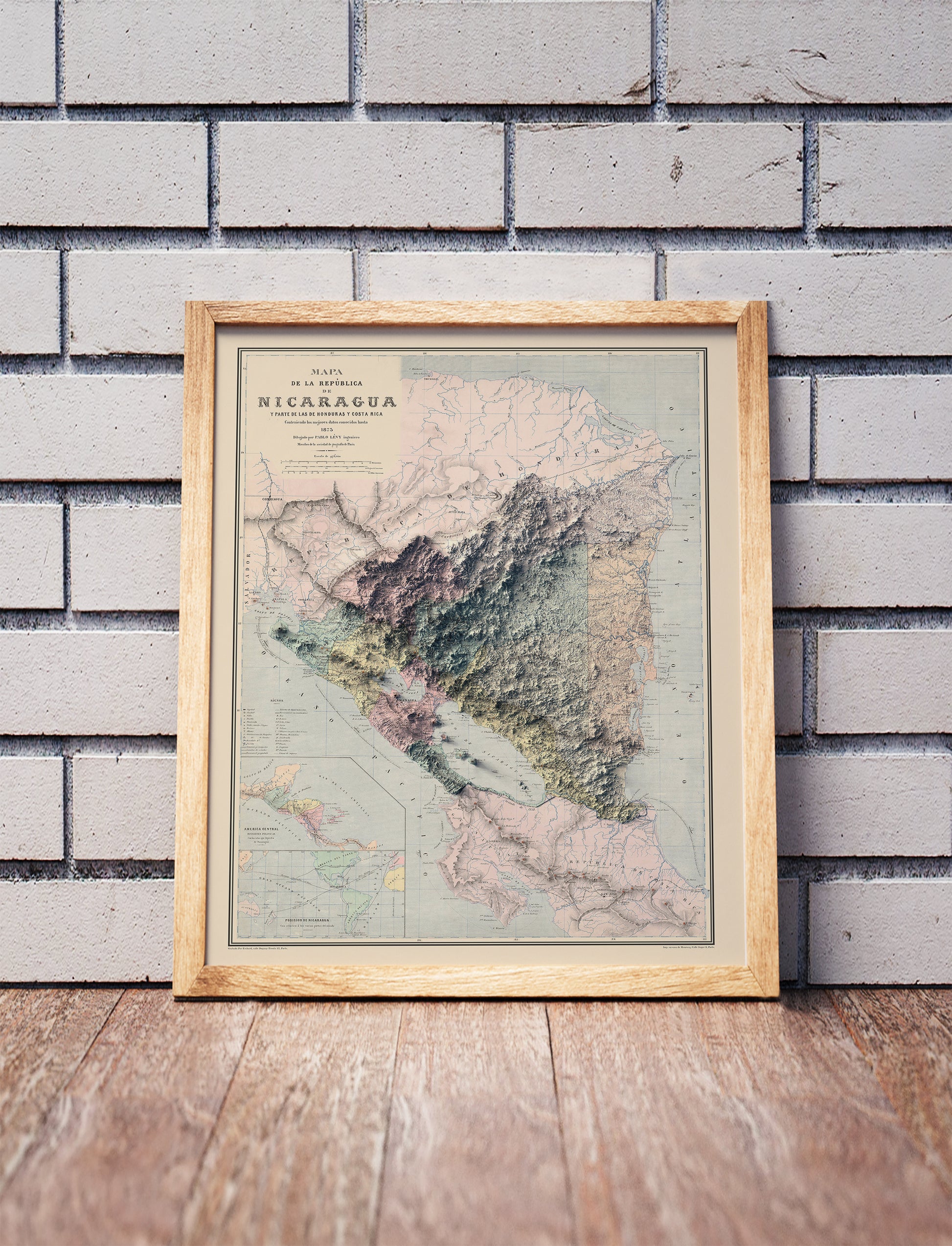 Vintage Nicaragua shaded relief map in a wooden frame. Realistic terrain art print for home decor, displayed against a brick wall