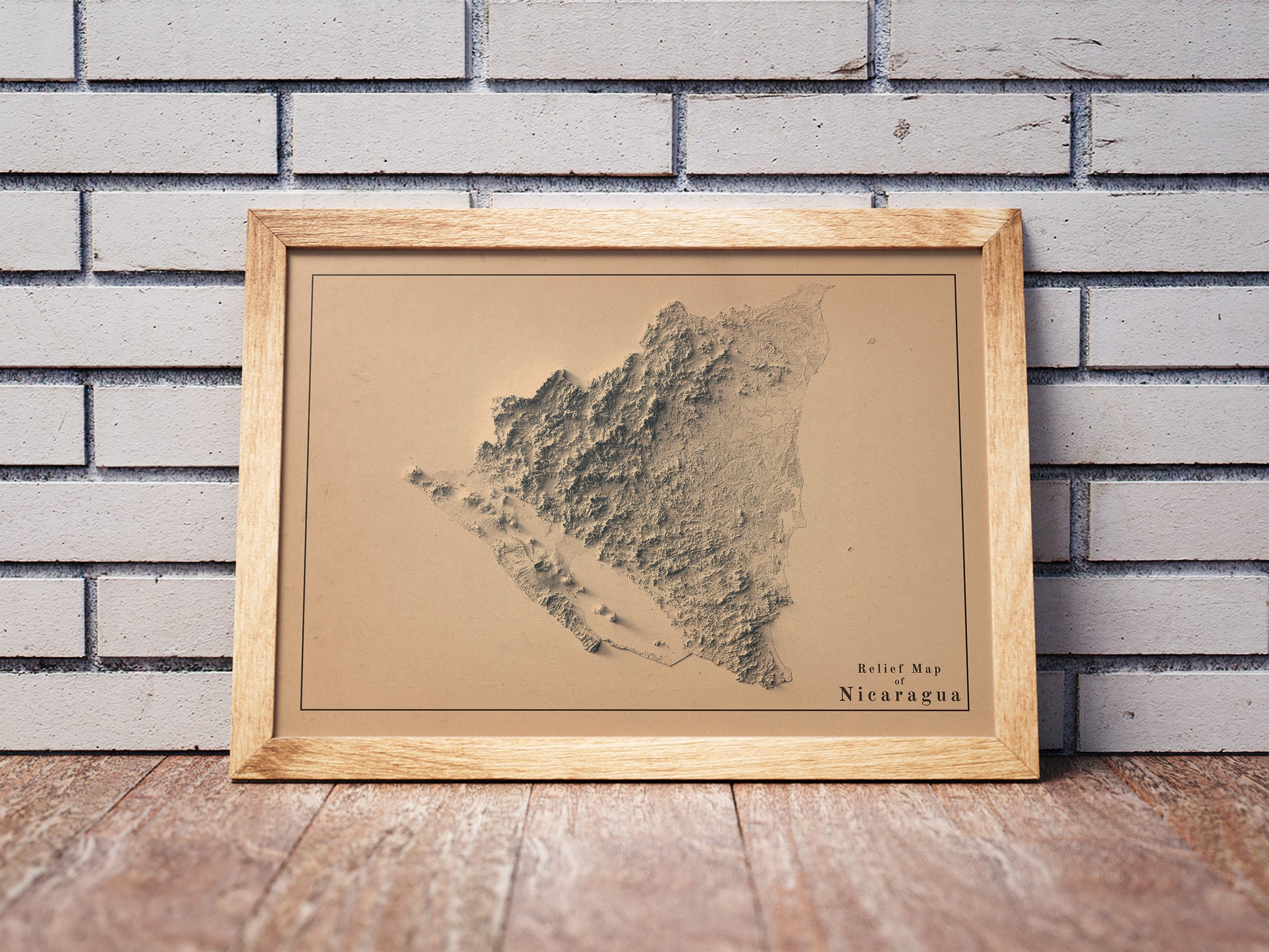 Vintage Nicaragua shaded relief map in a wooden frame. Realistic terrain art print for home decor, displayed against a brick wall