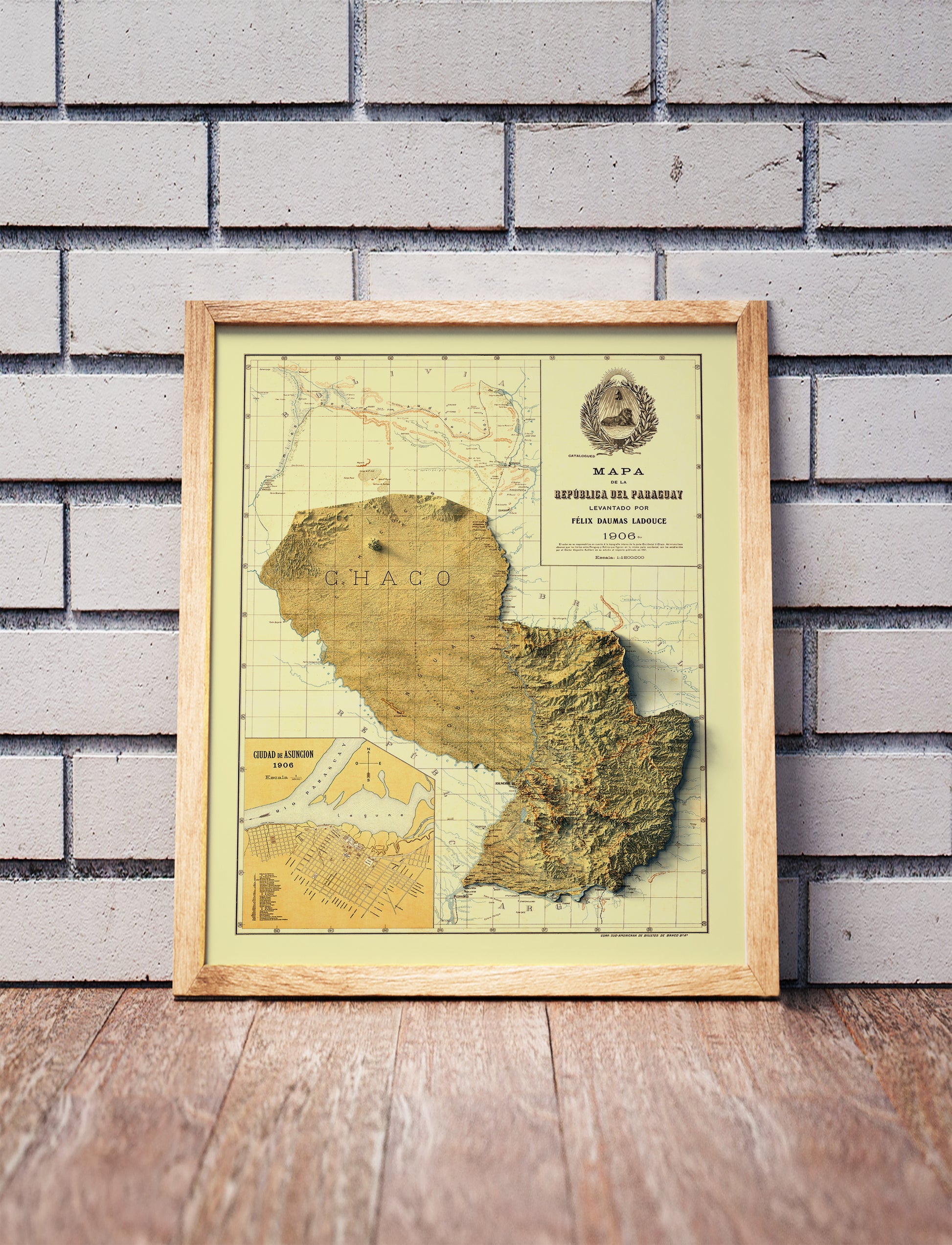Vintage Paraguay shaded relief map in a wooden frame. Realistic terrain art print for home decor, displayed against a brick wall