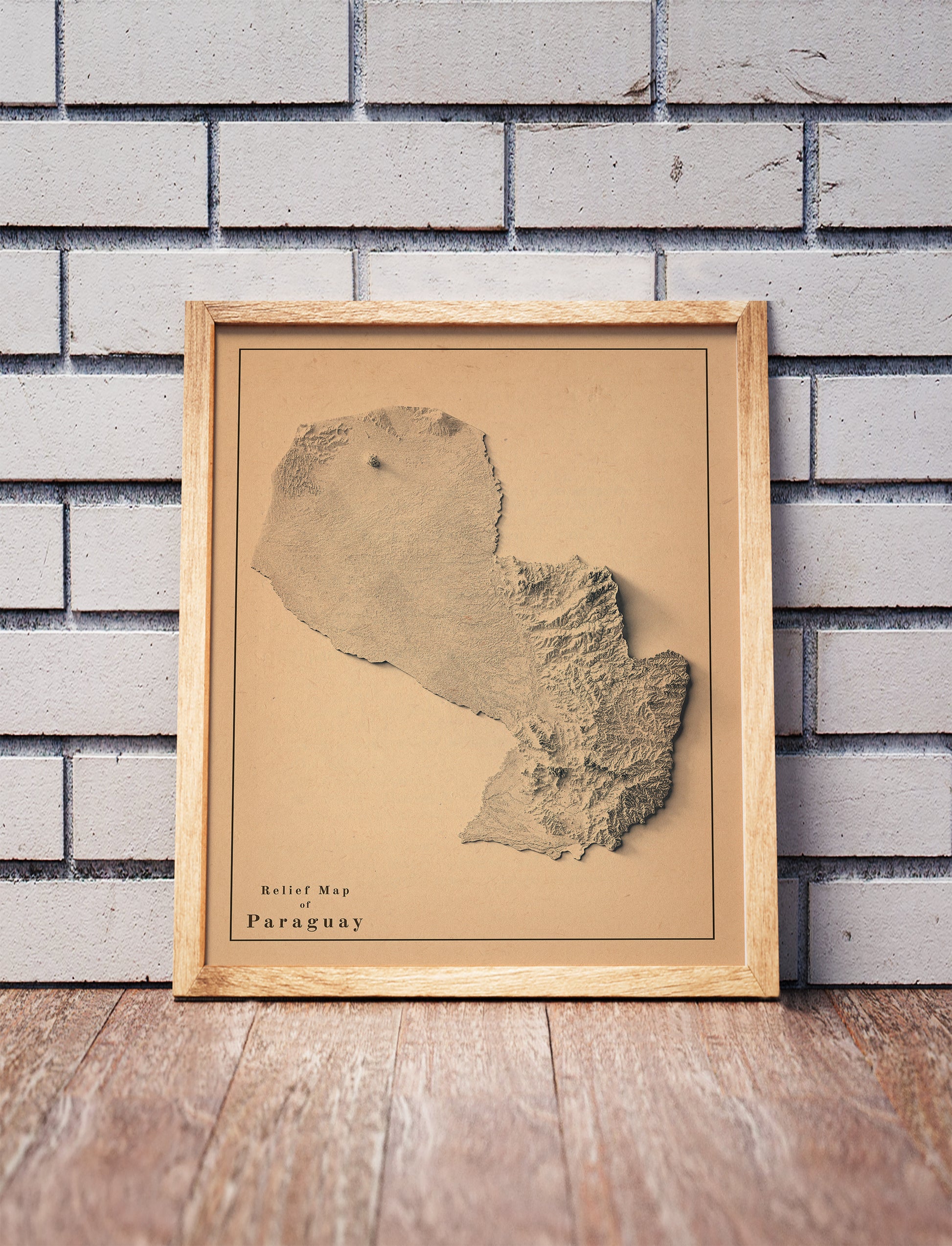 Vintage Paraguay shaded relief map in a wooden frame. Realistic terrain art print for home decor, displayed against a brick wall