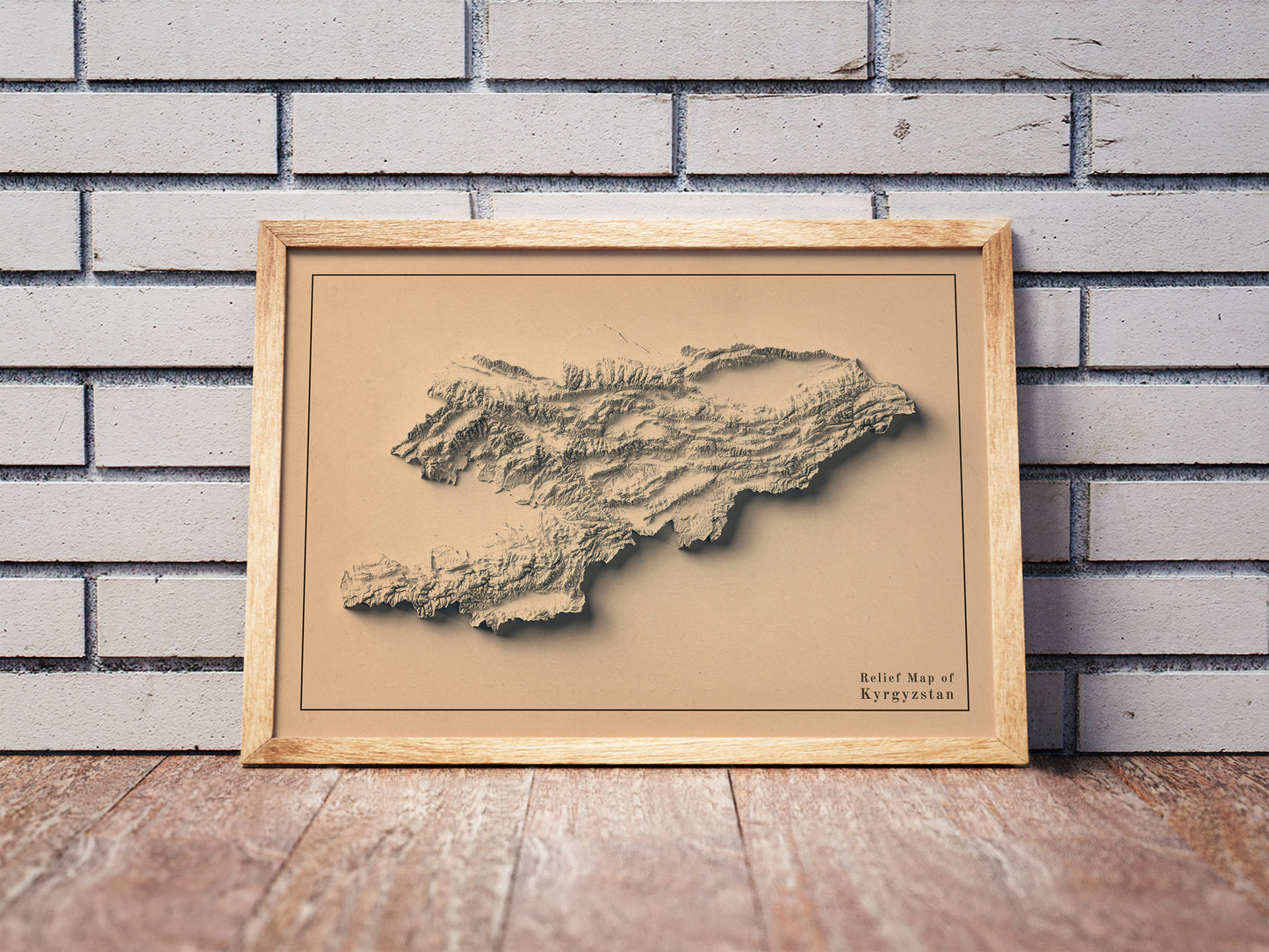 Vintage Kyrgyzstan shaded relief map in a wooden frame. Realistic terrain art print for home decor, displayed against a brick wall