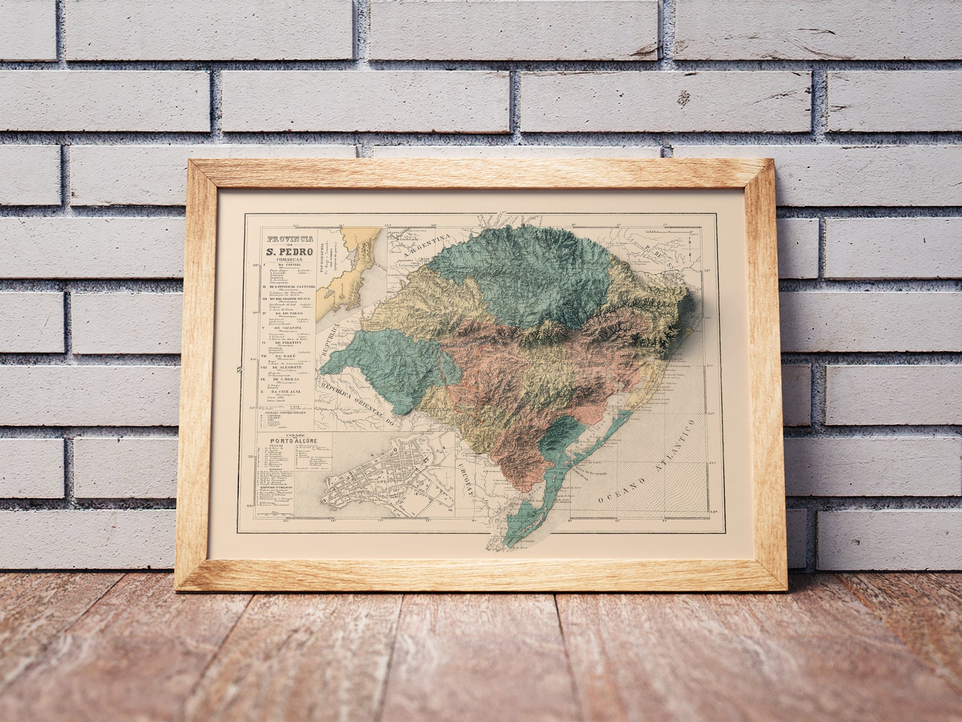 Vintage Rio Grande do Sul State shaded relief map in a wooden frame. Realistic terrain art print for home decor, displayed against a brick wall