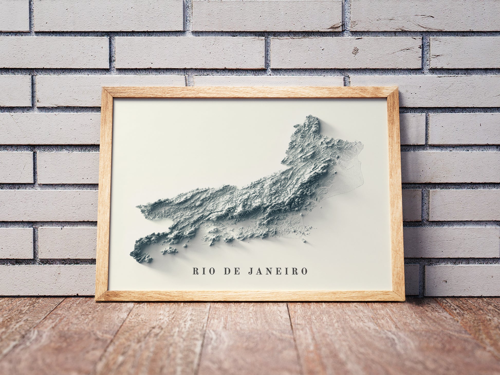 Rio de Janeiro State shaded relief map in a wooden frame. Realistic terrain art print for home decor, displayed against a brick wall