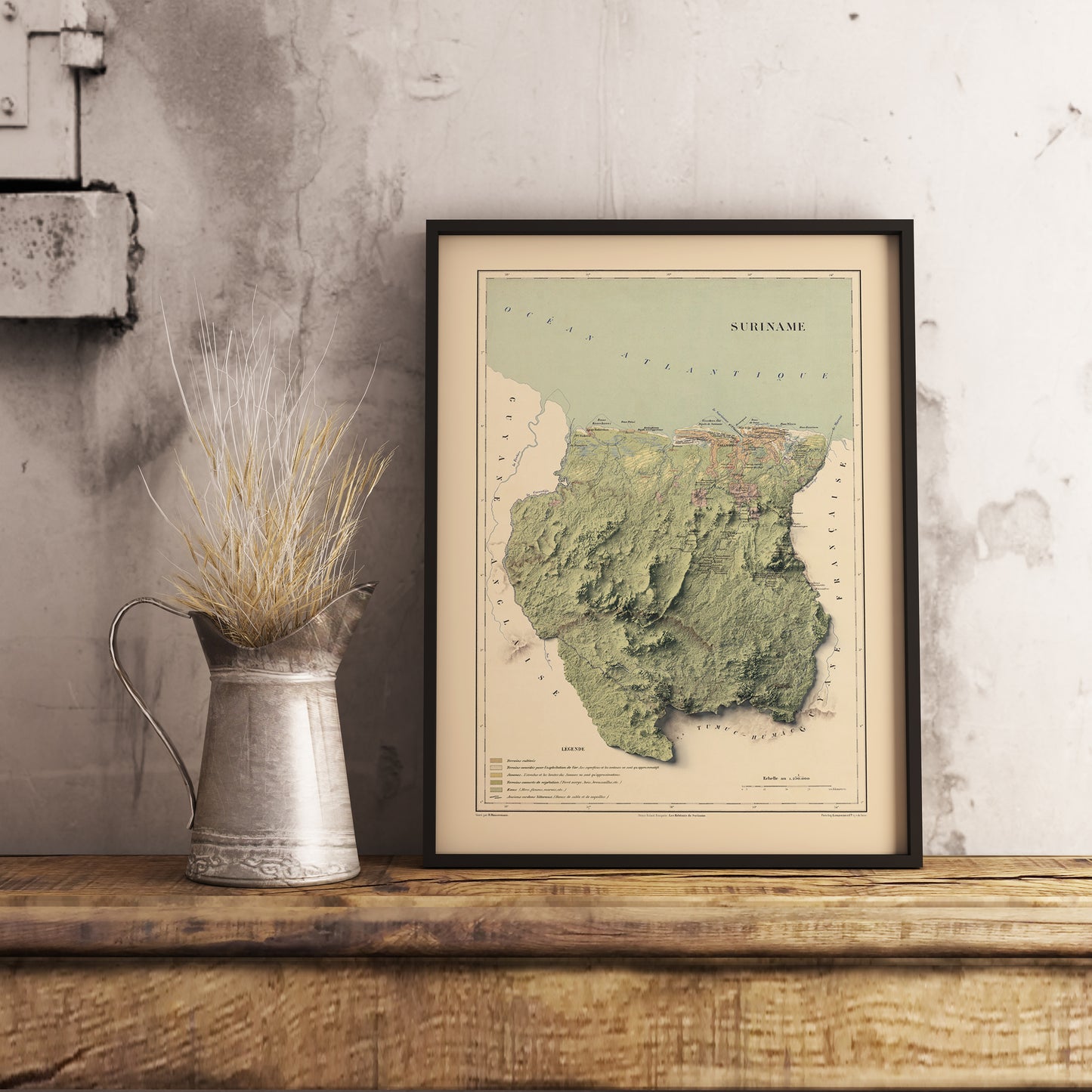 Vintage Suriname shaded relief map in black frame. Realistic terrain art print for home decor, displayed on rustic wooden table