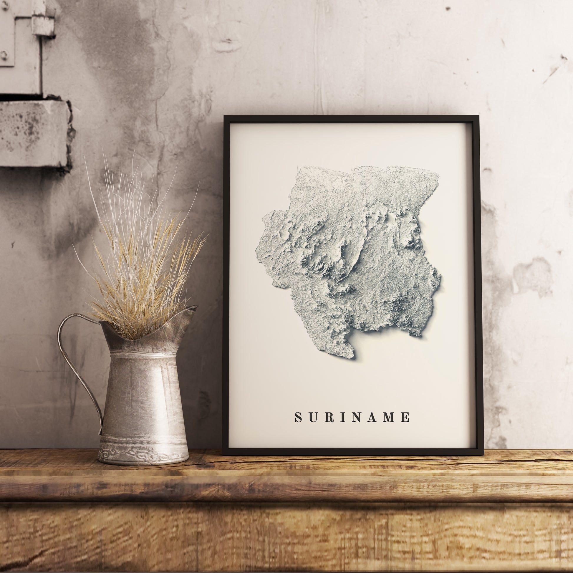 Suriname shaded relief map in black frame. Realistic terrain art print for home decor, displayed on rustic wooden table