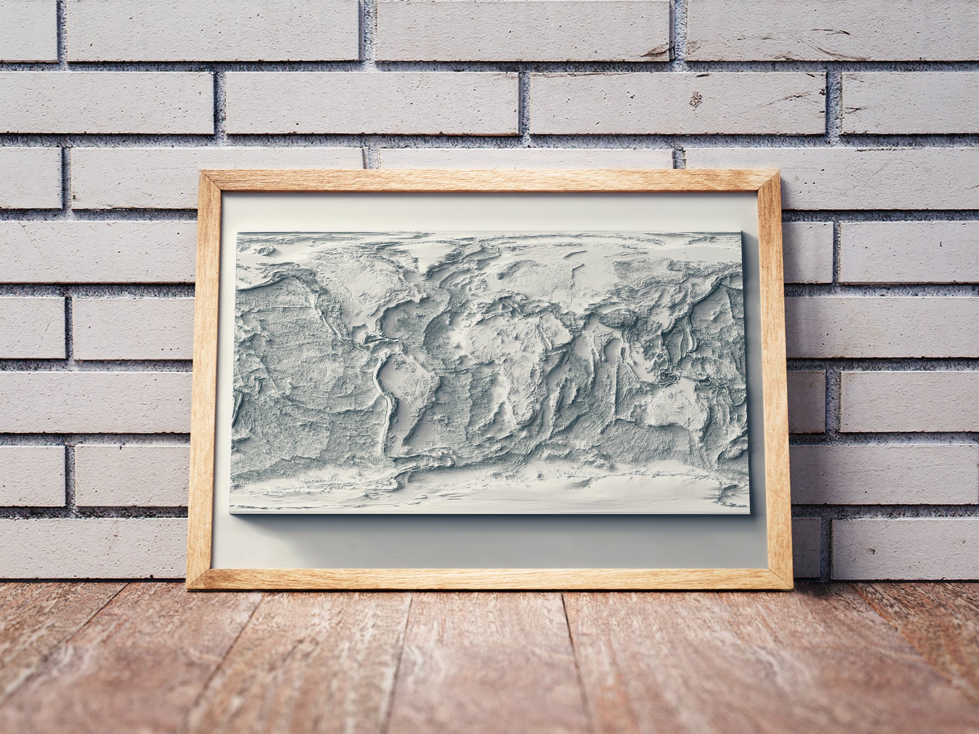 World Bathymetric shaded relief map in a wooden frame. Realistic terrain art print for home decor, displayed against a brick wall