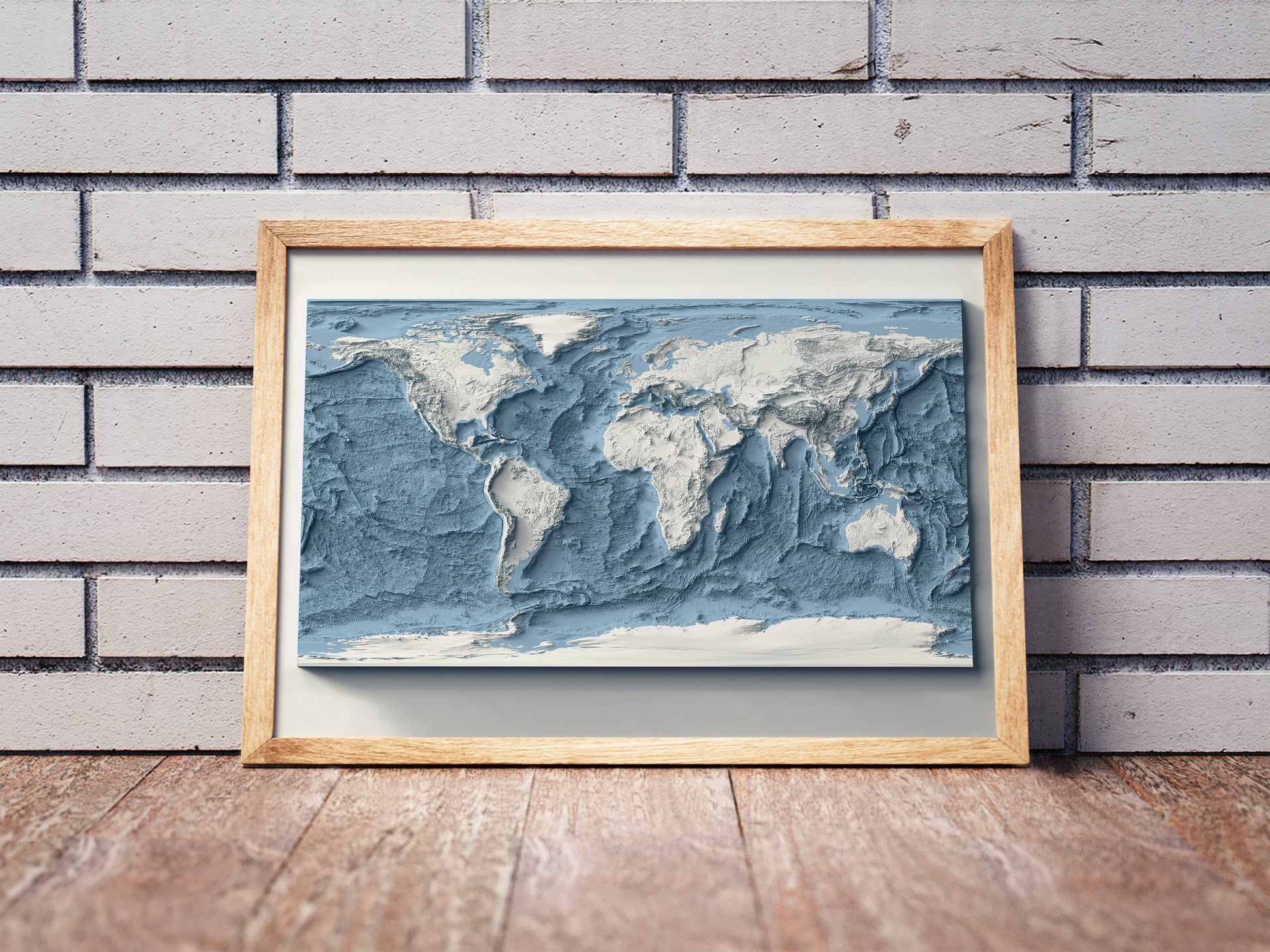 World Bathymetric shaded relief map in a wooden frame. Realistic terrain art print for home decor, displayed against a brick wall