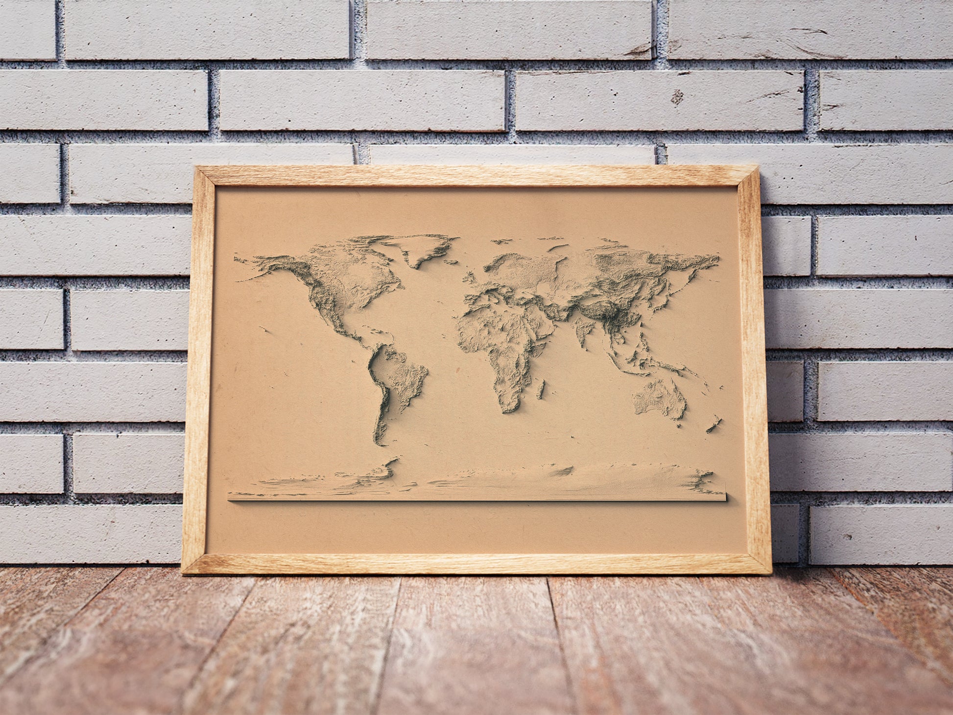 Vintage World shaded relief map in a wooden frame. Realistic terrain art print for home decor, displayed against a brick wall