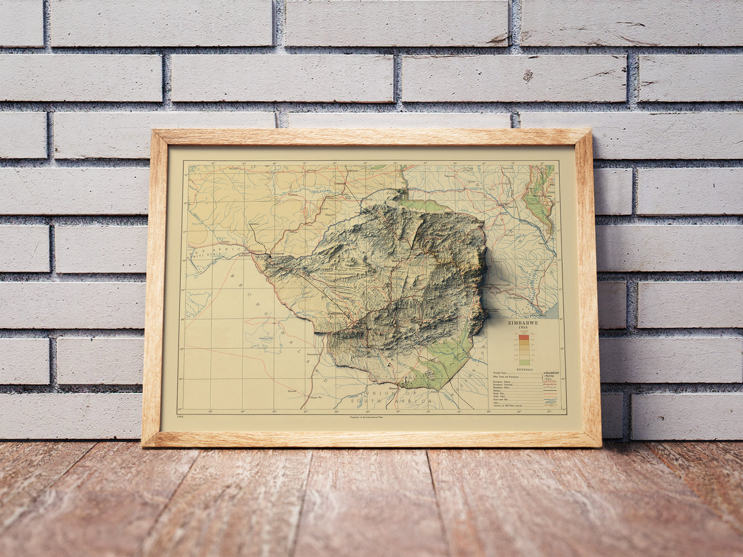 Vintage Zimbabwe shaded relief map in a wooden frame. Realistic terrain art print for home decor, displayed against a brick wall