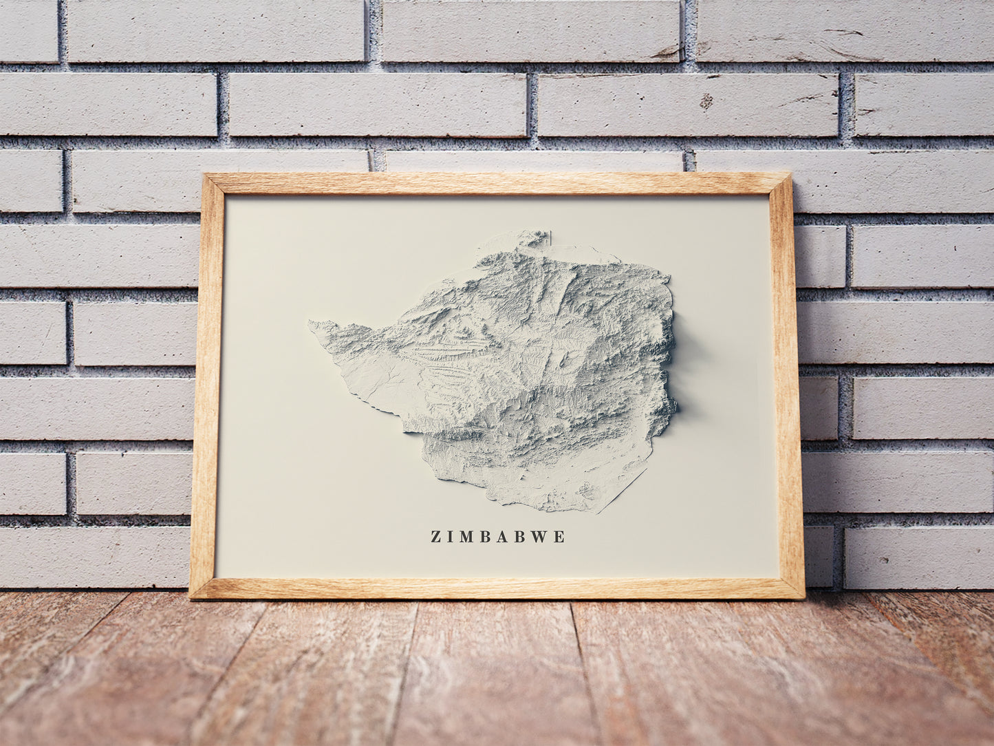 Zimbabwe shaded relief map in a wooden frame. Realistic terrain art print for home decor, displayed against a brick wall