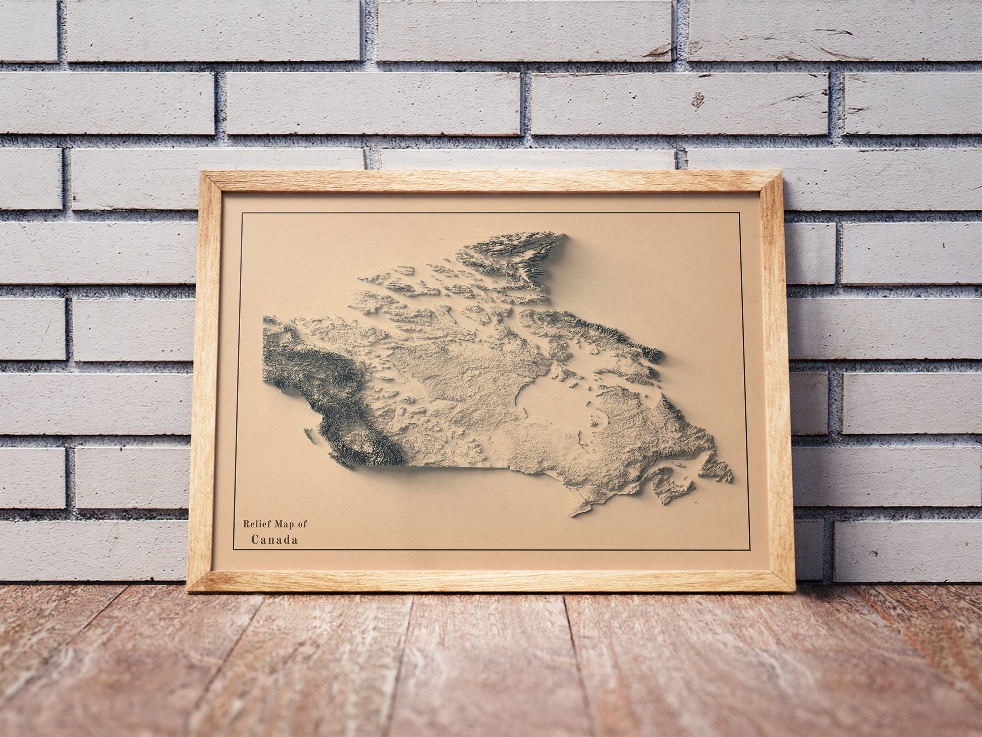 Vintage Canada shaded relief map in a wooden frame. Realistic terrain art print for home decor, displayed against a brick wall