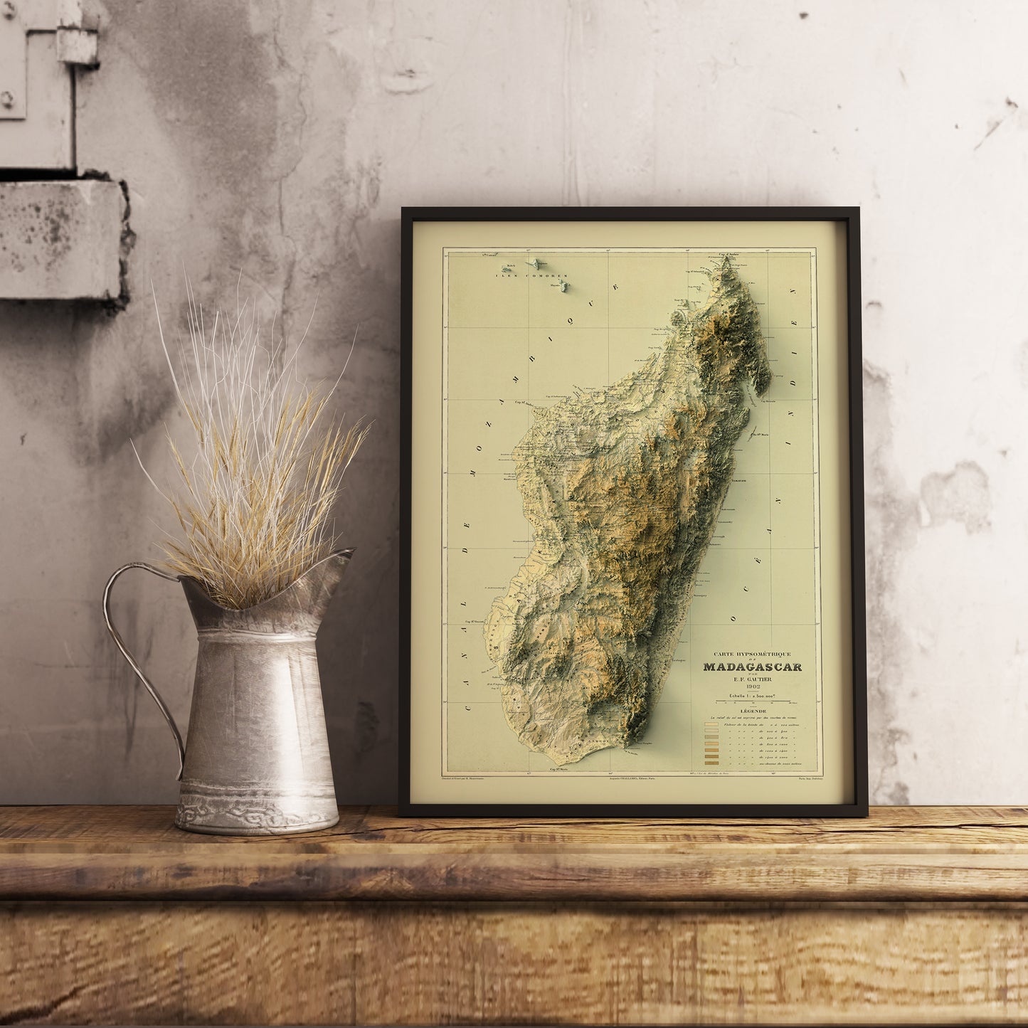 Vintage Madagascar shaded relief map in black frame. Realistic terrain art print for home decor, displayed on rustic wooden table