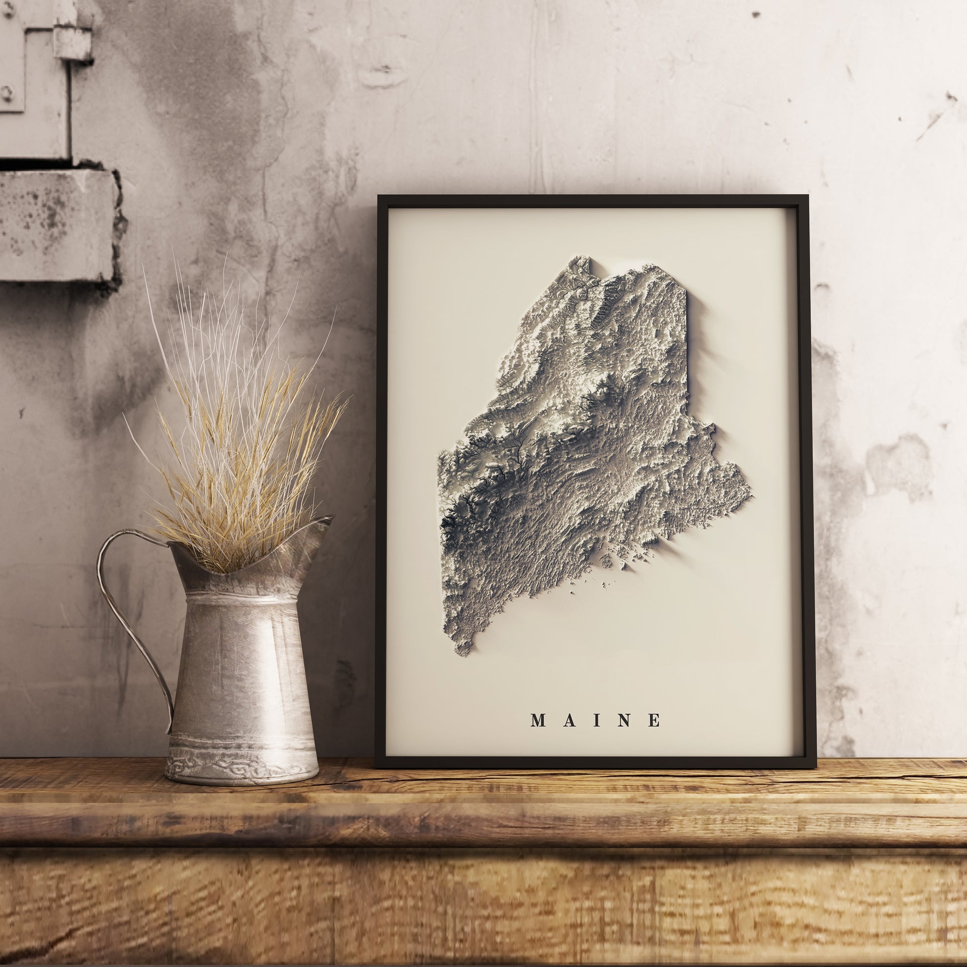 Maine shaded relief map in black frame. Realistic terrain art print for home decor, displayed on rustic wooden table