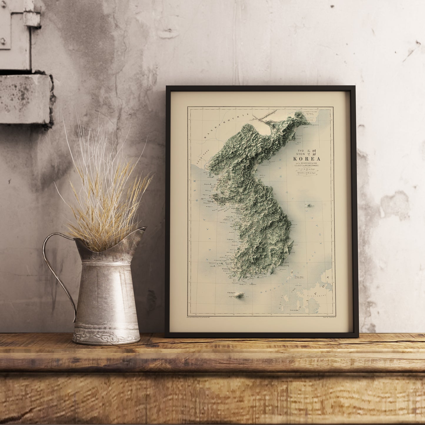 Vintage North and South Koreas shaded relief map in black frame. Realistic terrain art print for home decor, displayed on rustic wooden table