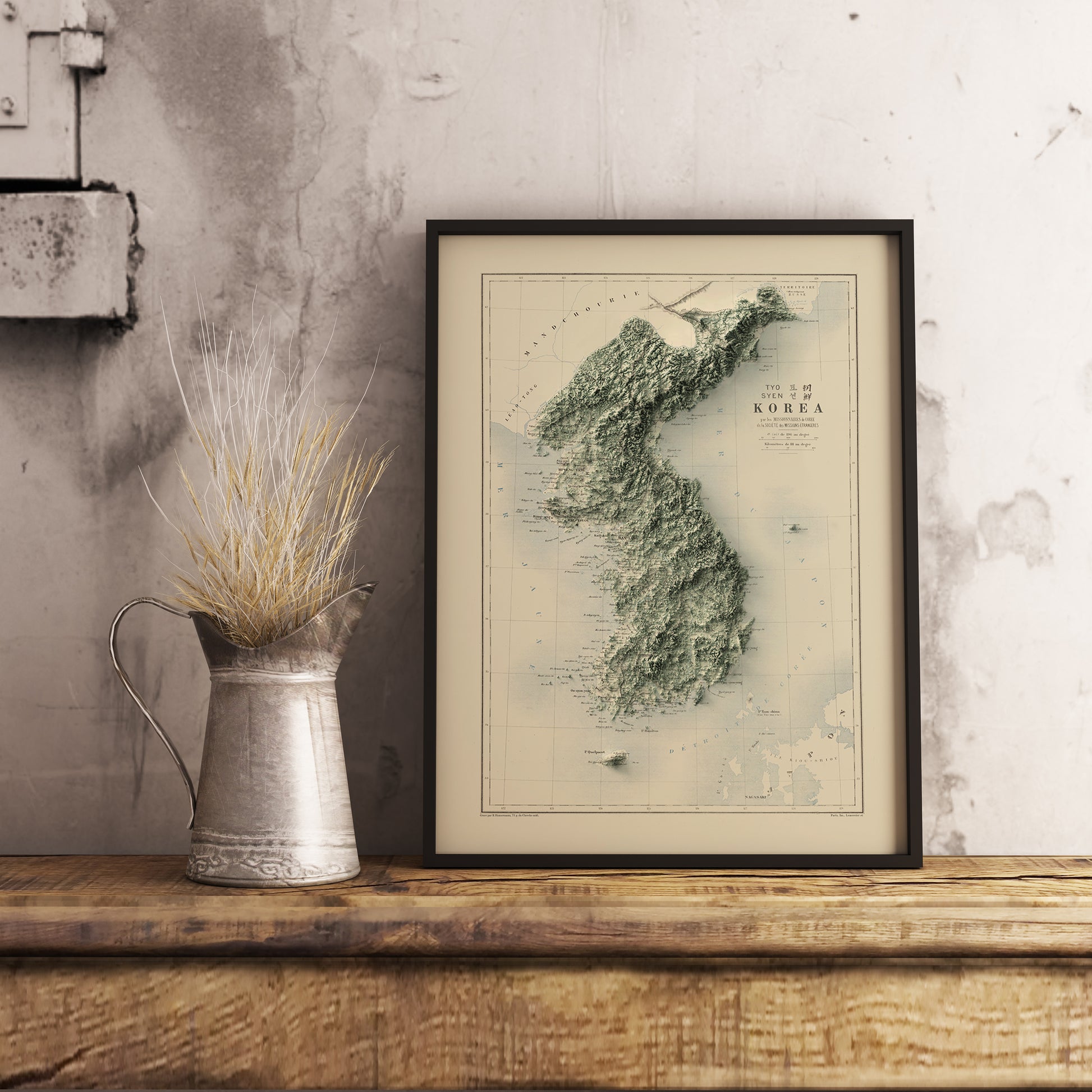 Vintage North and South Koreas shaded relief map in black frame. Realistic terrain art print for home decor, displayed on rustic wooden table