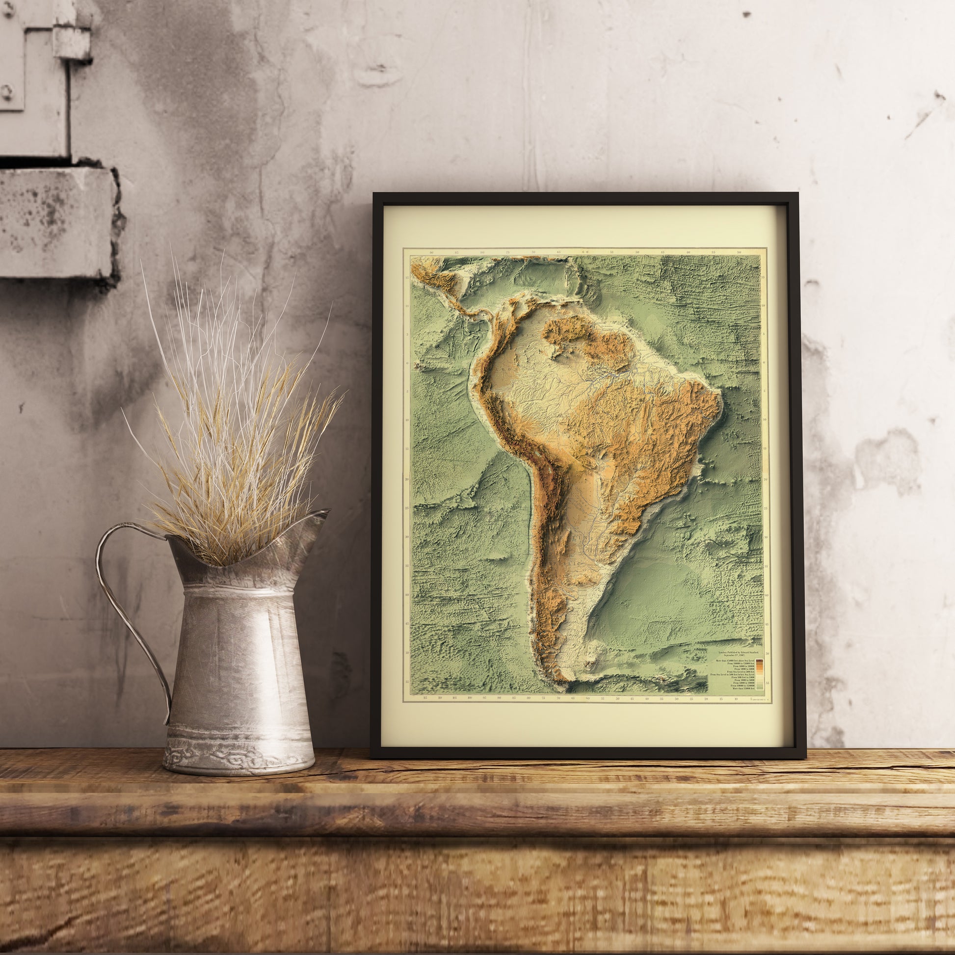 Vintage South America Bathymetrical shaded relief map in black frame. Realistic terrain art print for home decor, displayed on rustic wooden table