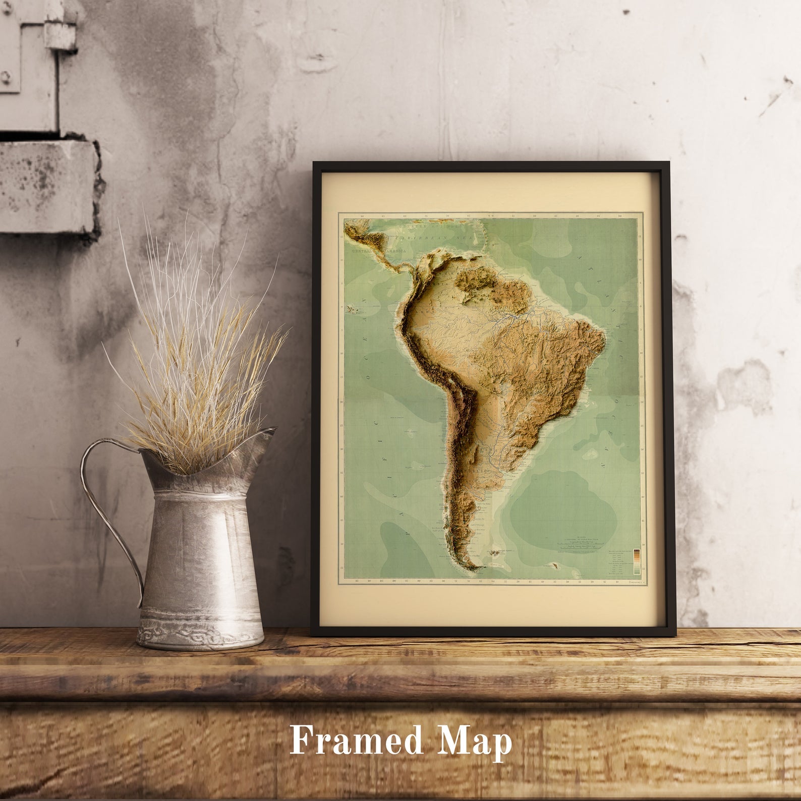 Vintage South America shaded relief map in black frame. Realistic terrain art print for home decor, displayed on rustic wooden table