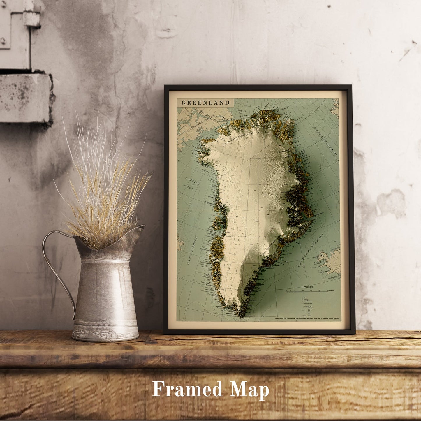 Vintage Greenland shaded relief map in black frame. Realistic terrain art print for home decor, displayed on rustic wooden table