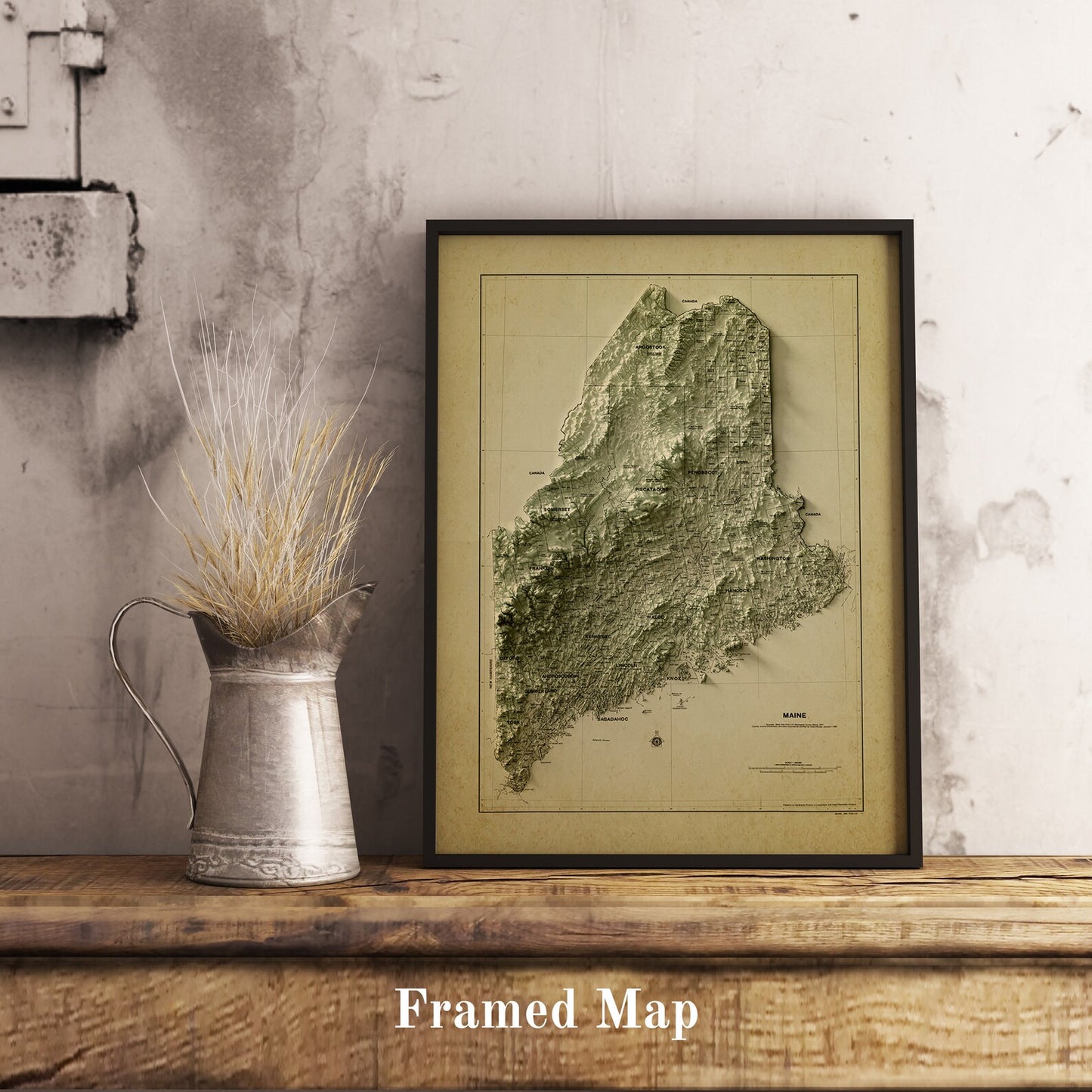 Vintage Maine shaded relief map in black frame. Realistic terrain art print for home decor, displayed on rustic wooden table