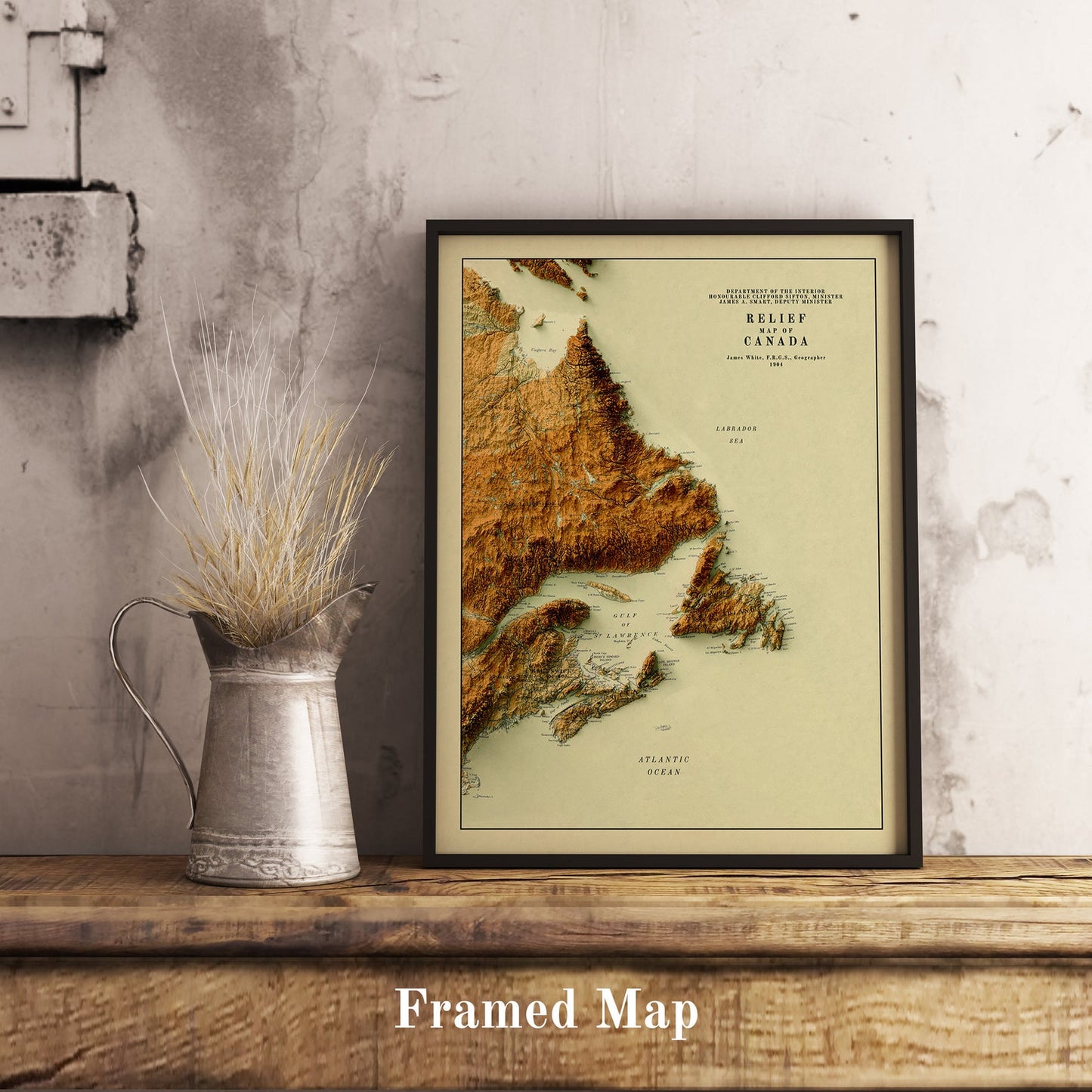 Vintage Atlantic Canada shaded relief map in black frame. Realistic terrain art print for home decor, displayed on rustic wooden table