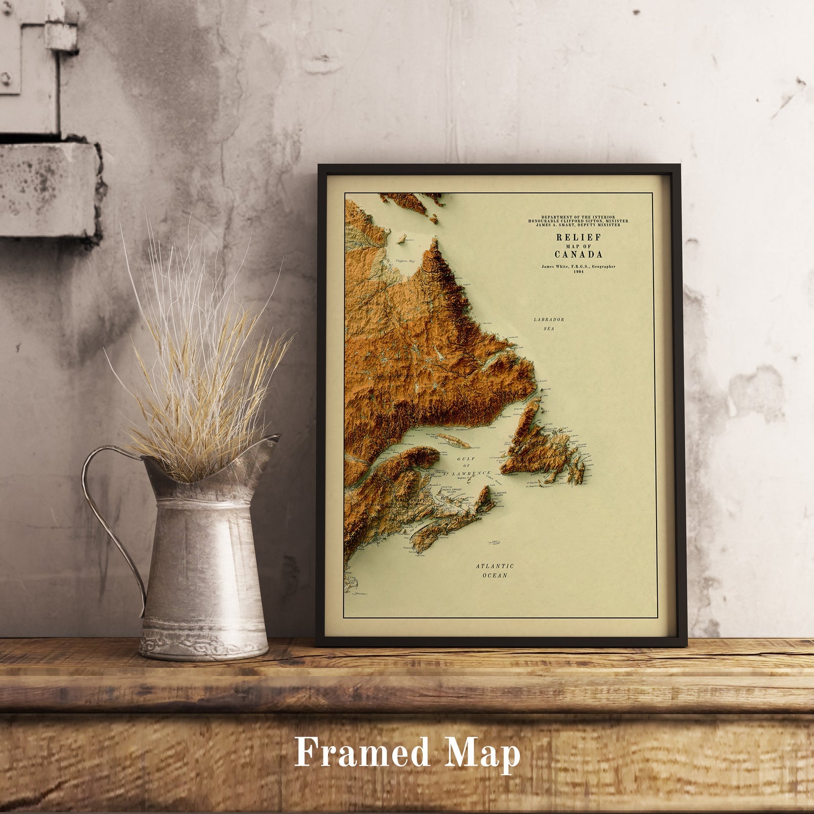 Vintage Atlantic Canada shaded relief map in black frame. Realistic terrain art print for home decor, displayed on rustic wooden table