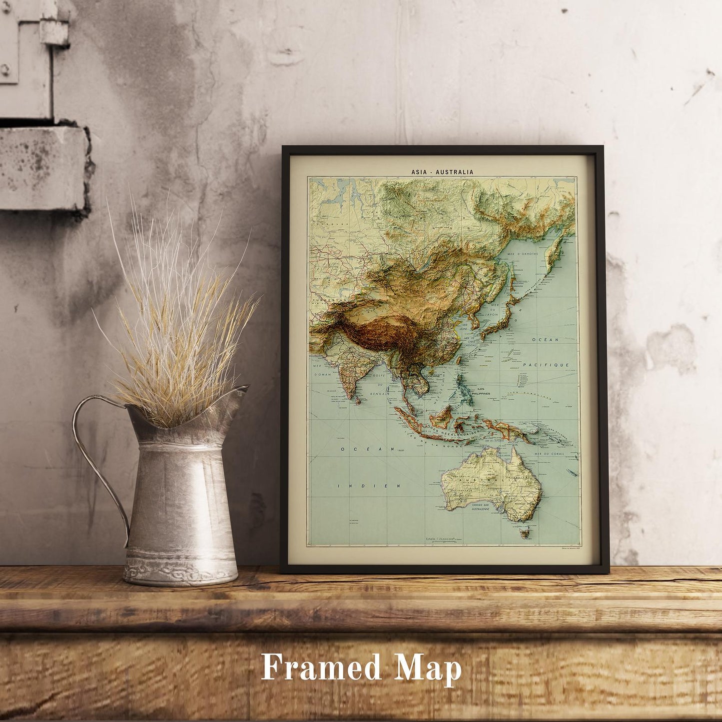 Vintage Asia and Australia shaded relief map in black frame. Realistic terrain art print for home decor, displayed on rustic wooden table