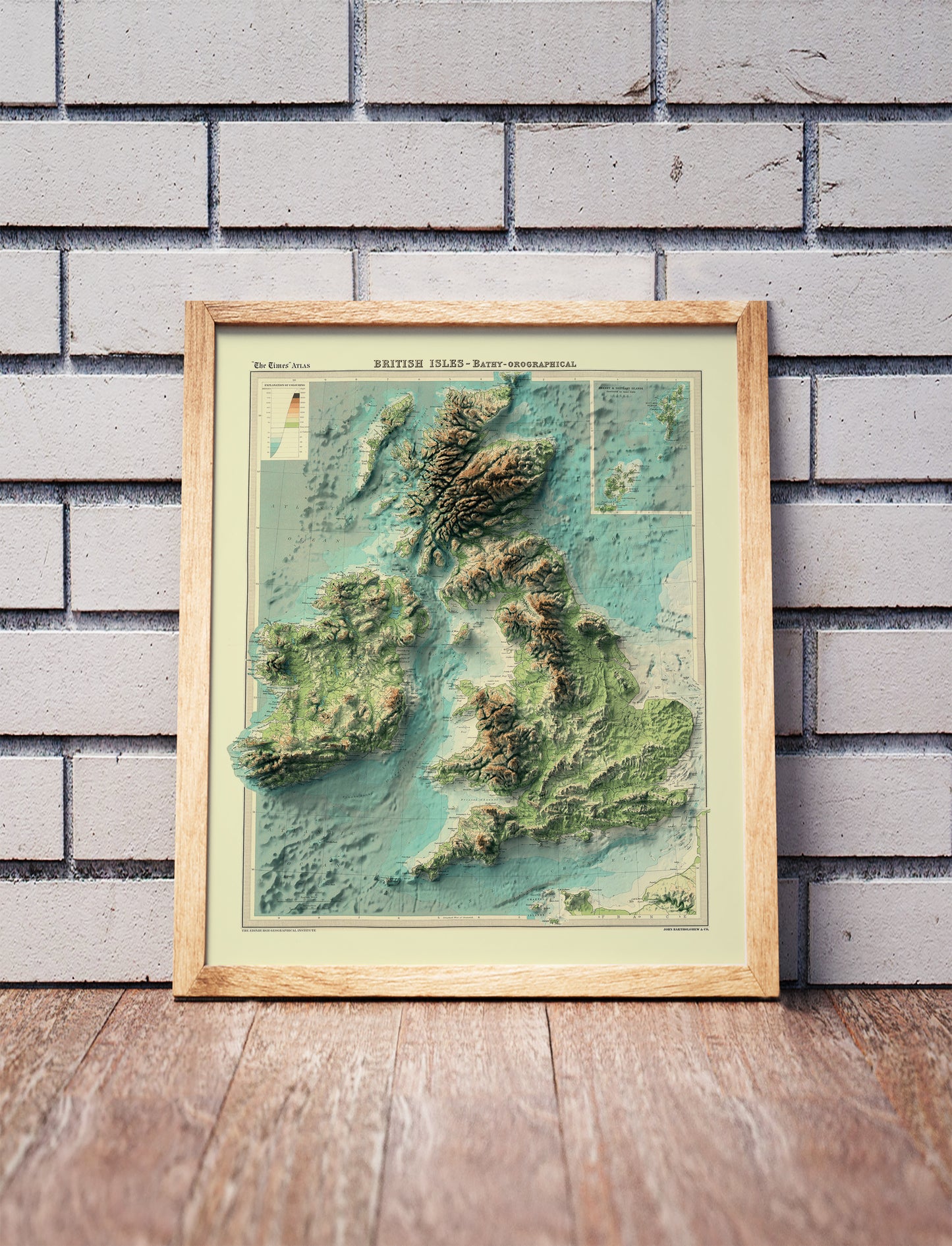 England, Ireland, Scotland and Wales shaded relief map in a wooden frame. Realistic terrain art print for home decor, displayed against a brick wall