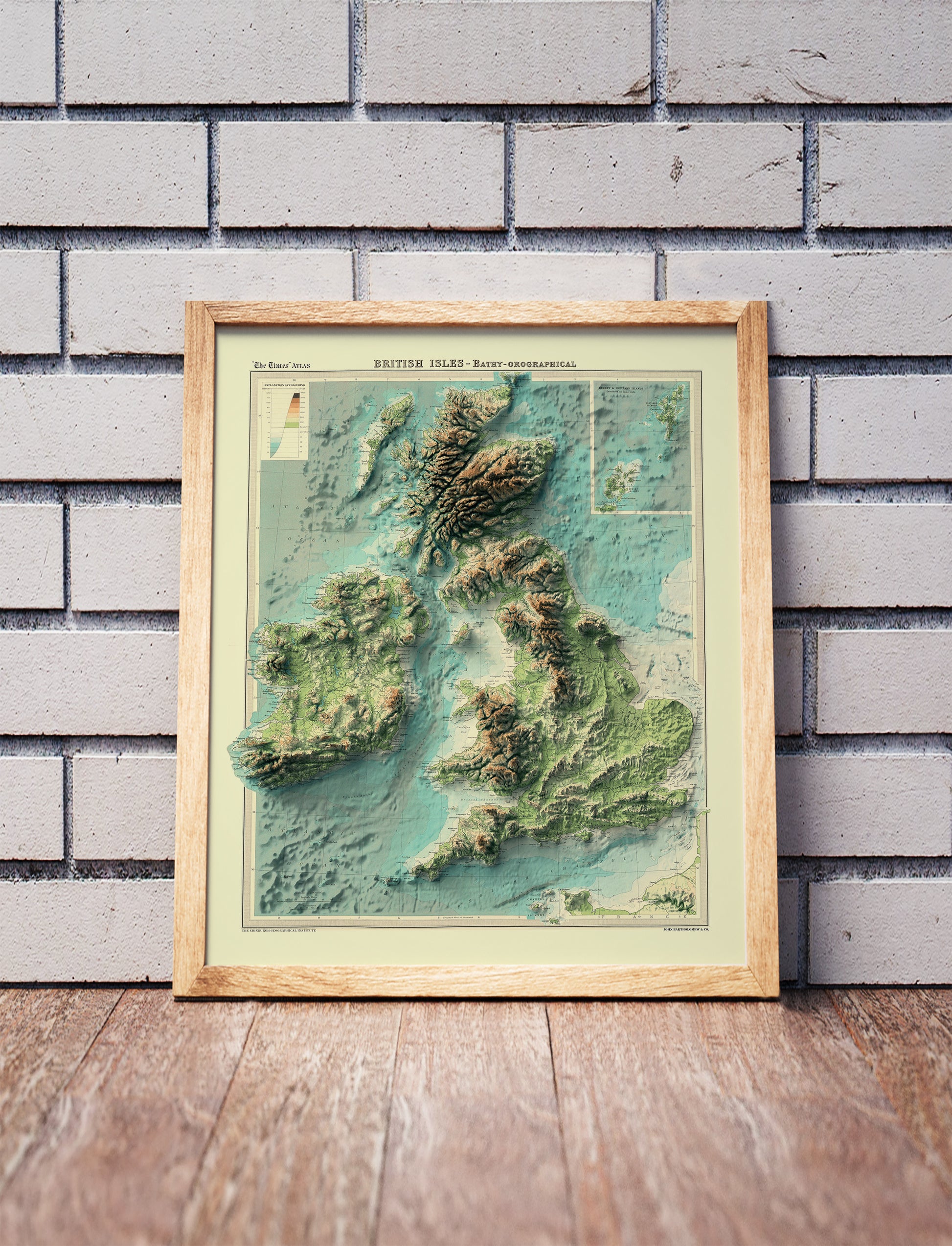 England, Ireland, Scotland and Wales shaded relief map in a wooden frame. Realistic terrain art print for home decor, displayed against a brick wall