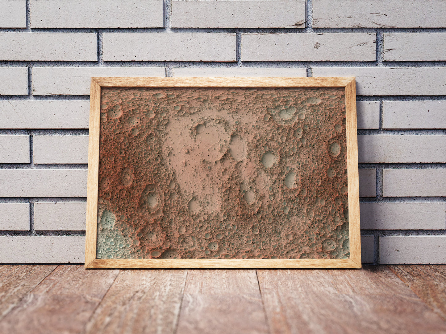 Moon shaded relief map in a wooden frame. Realistic terrain art print for home decor, displayed against a brick wall