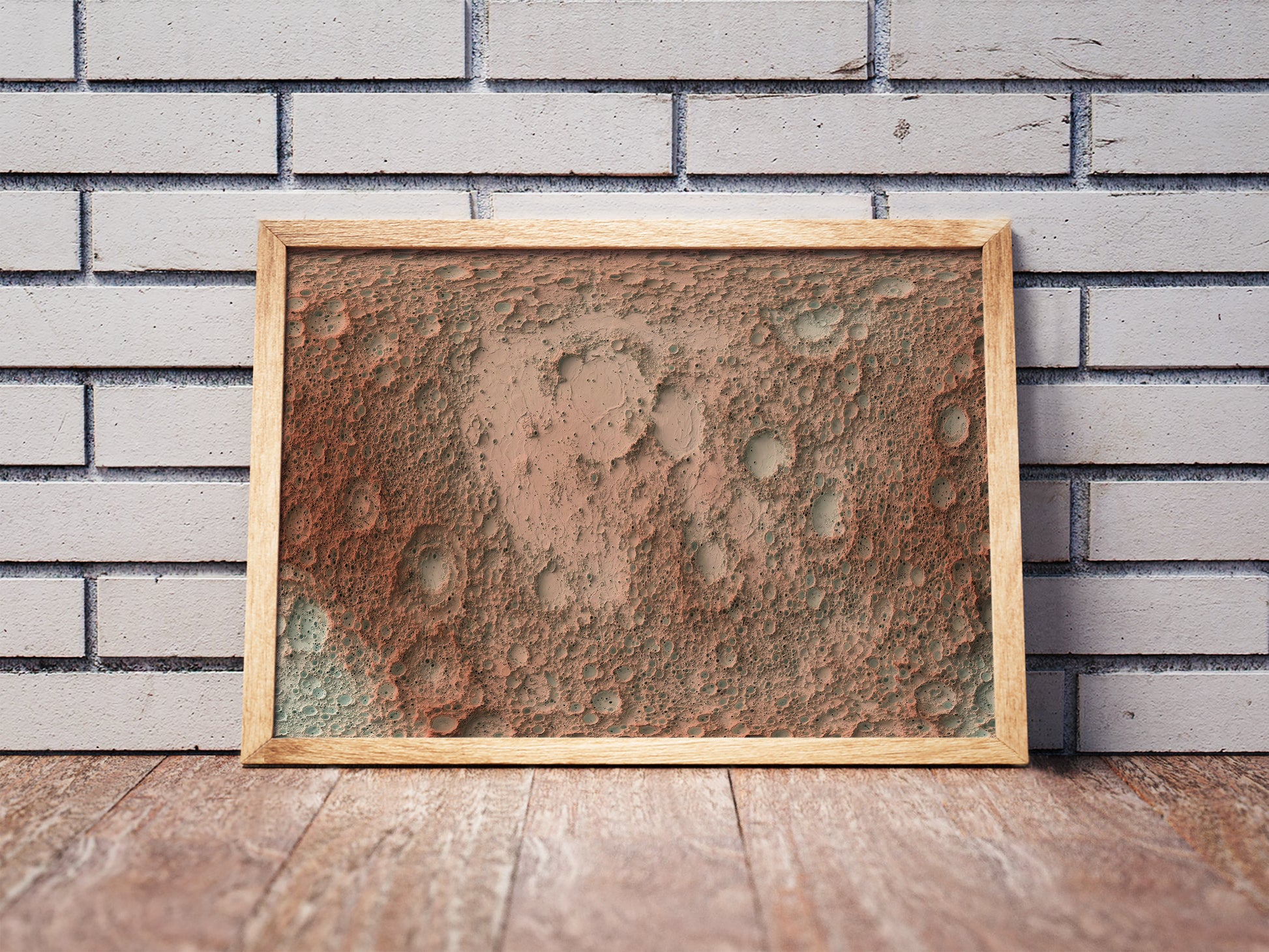 Moon shaded relief map in a wooden frame. Realistic terrain art print for home decor, displayed against a brick wall