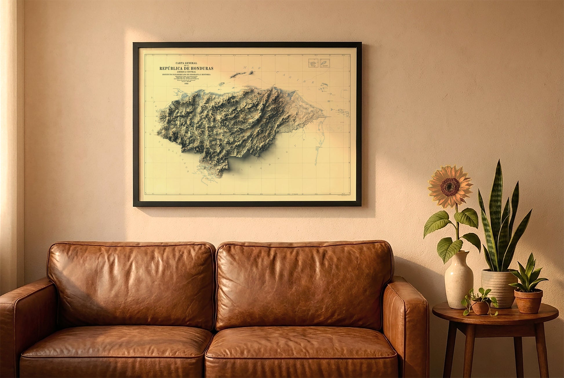 Honduras vintage relief map in a black frame above a brown leather sofa. Boho living room with warm sunlight, sunflower, and indoor plants on a wooden side table