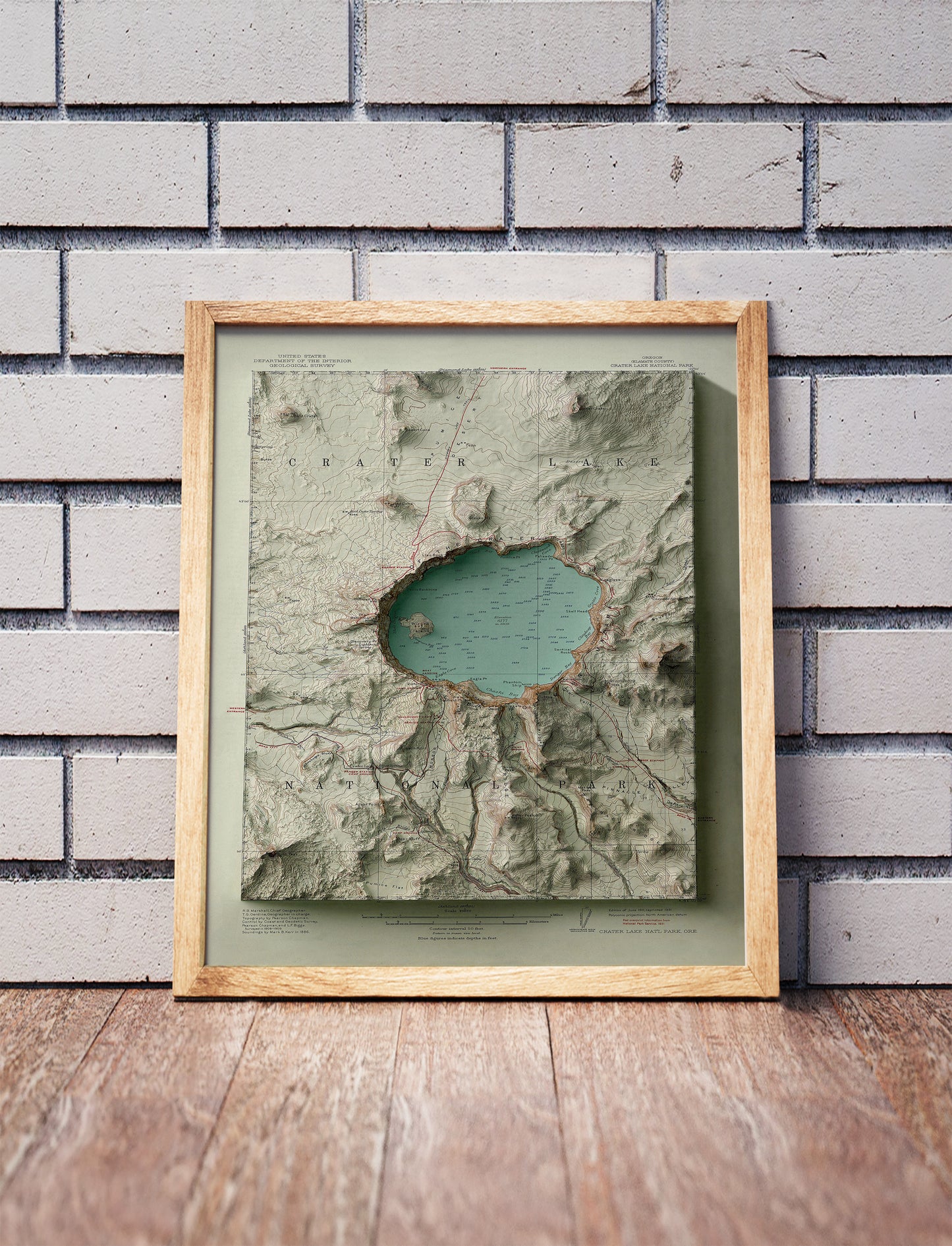 Vintage Crater Lake, Oregon, shaded relief map in a wooden frame. Realistic terrain art print for home decor, displayed against a brick wall