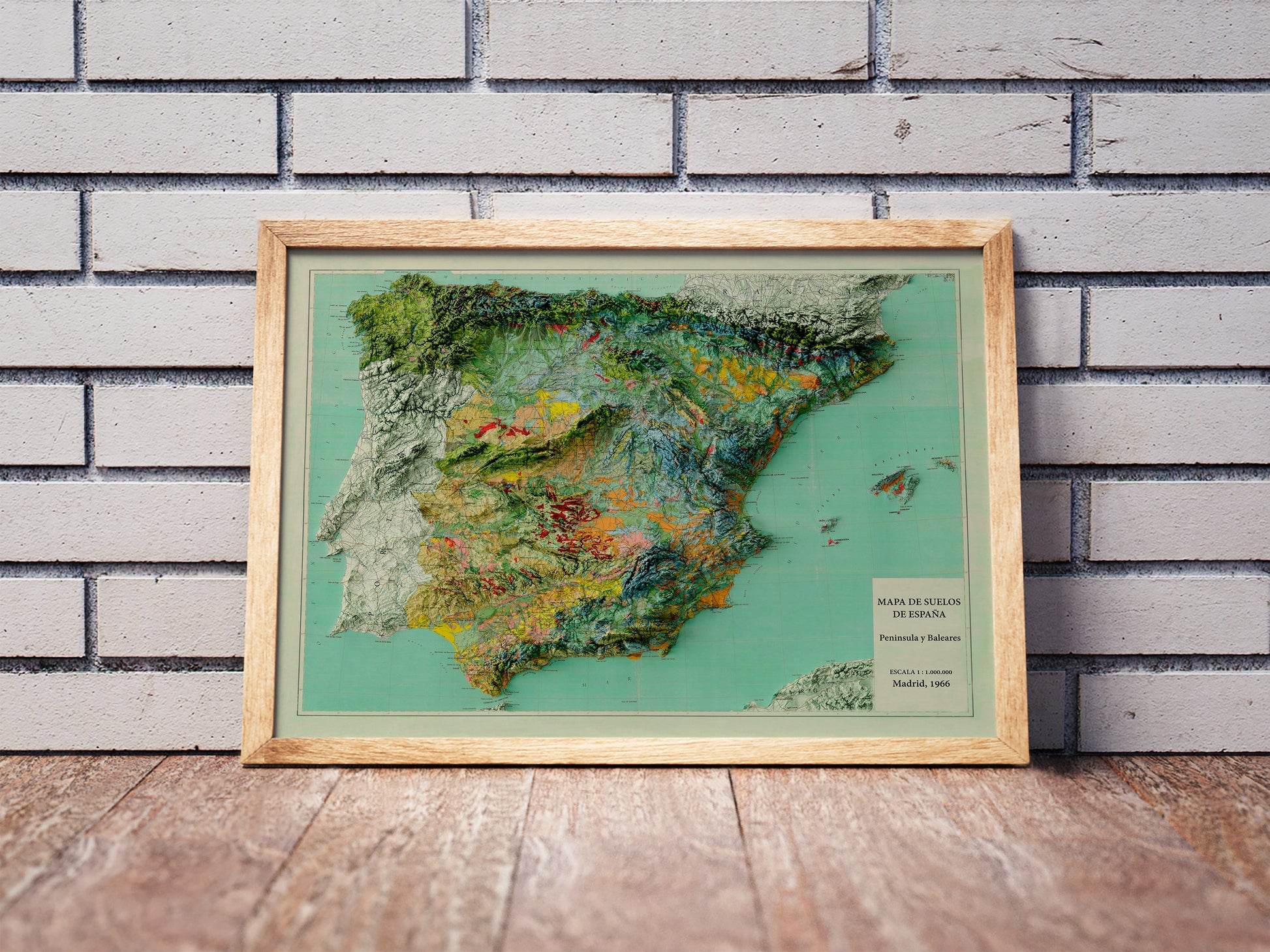 Vintage Spain shaded relief map in a wooden frame. Realistic terrain art print for home decor, displayed against a brick wall