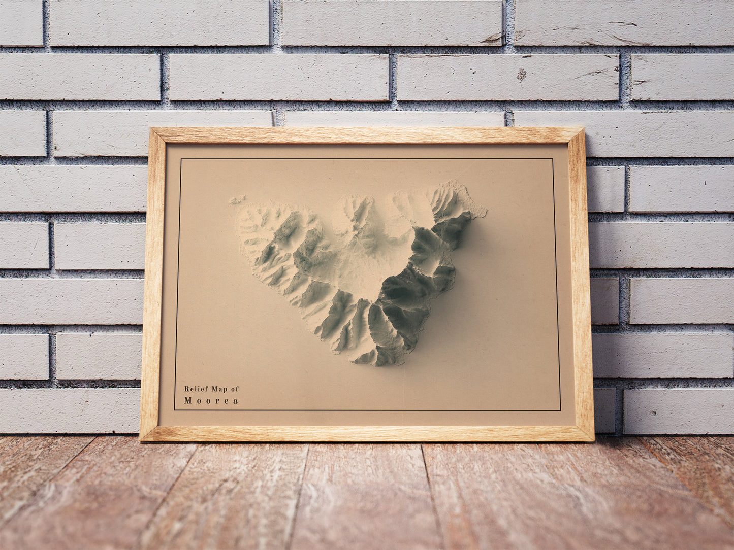 Vintage Moorea shaded relief map in a wooden frame. Realistic terrain art print for home decor, displayed against a brick wall