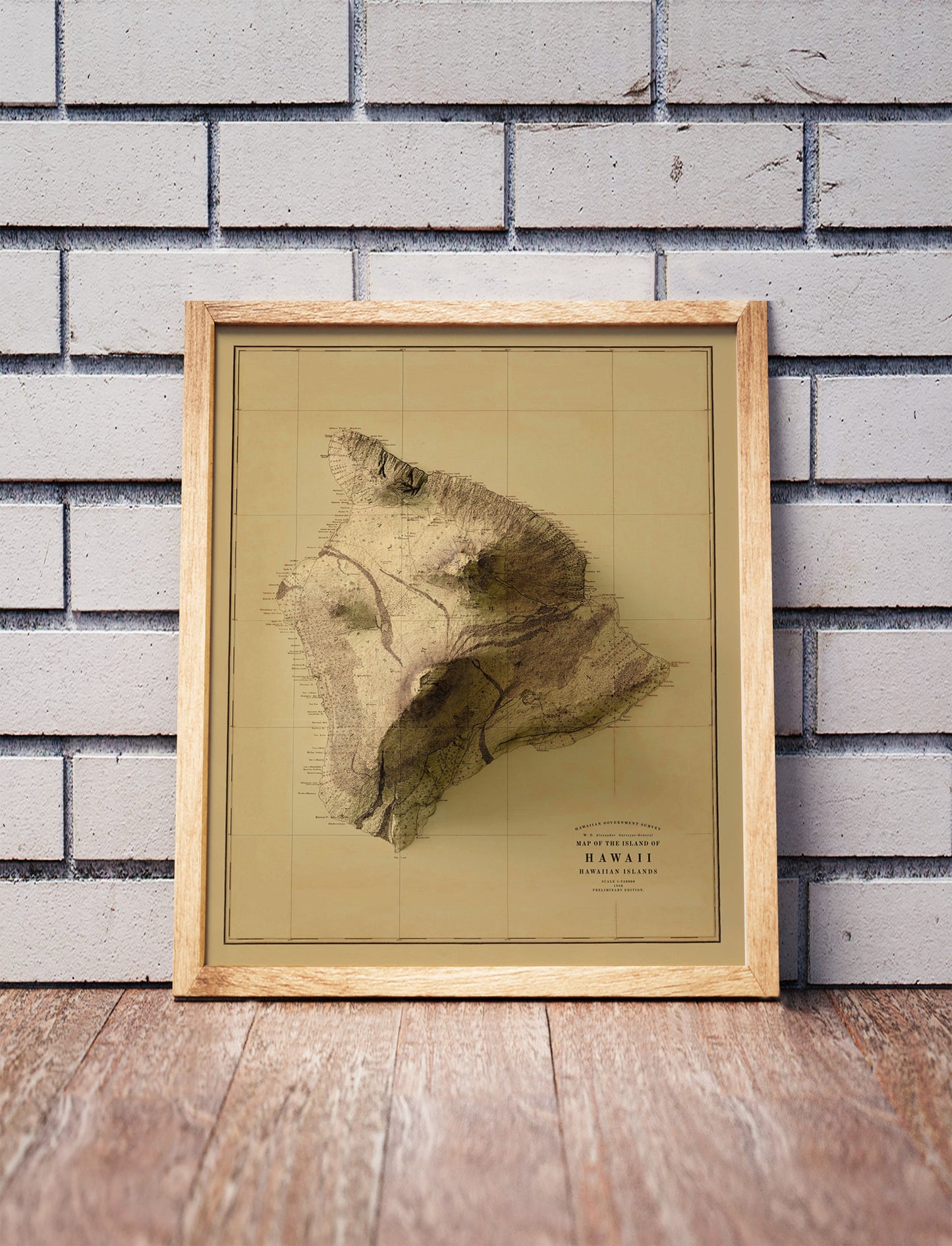 Vintage Hawaii Island shaded relief map in a wooden frame. Realistic terrain art print for home decor, displayed against a brick wall