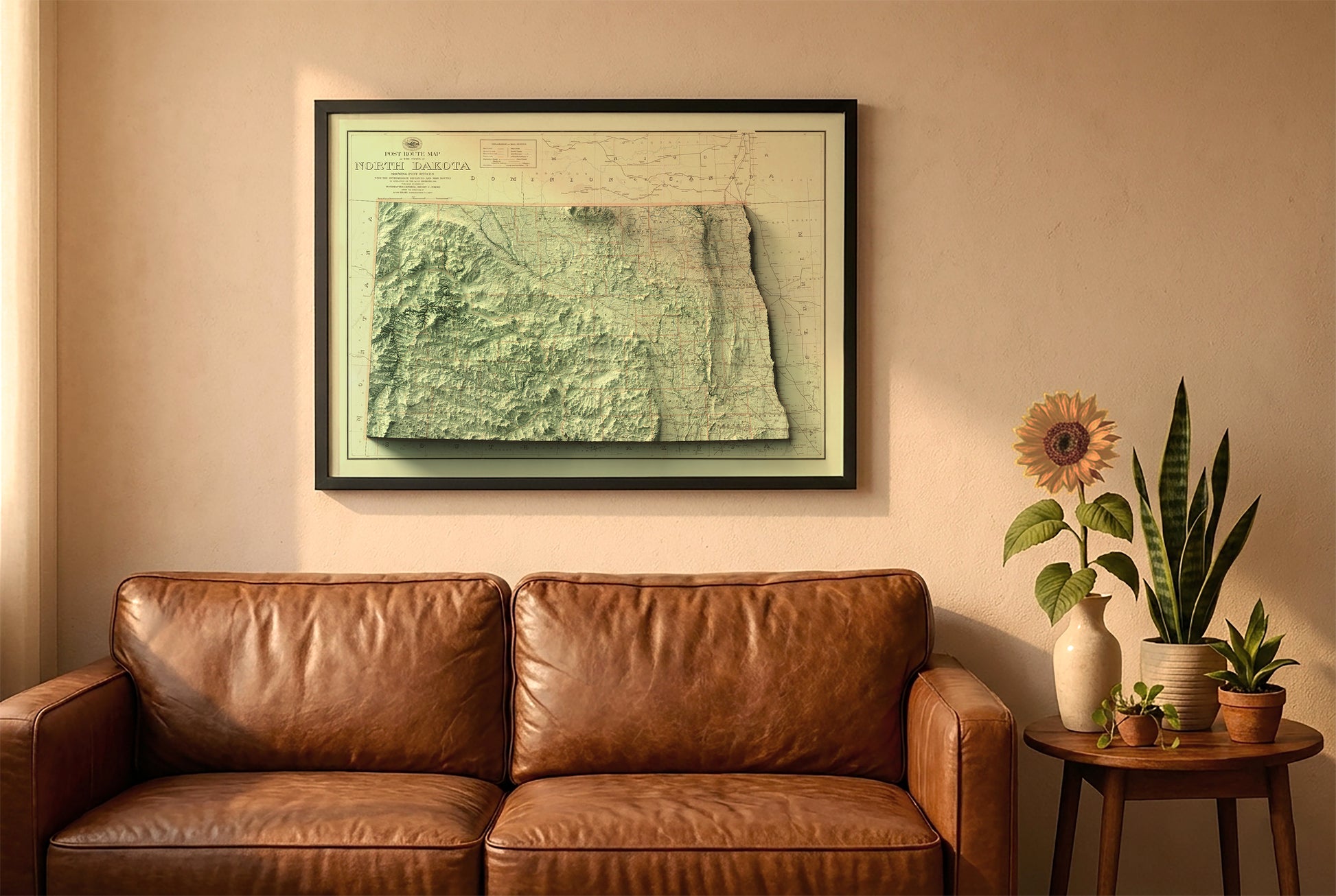 North Dakota vintage relief map in a black frame above a brown leather sofa. Boho living room with warm sunlight, sunflower, and indoor plants on a wooden side table